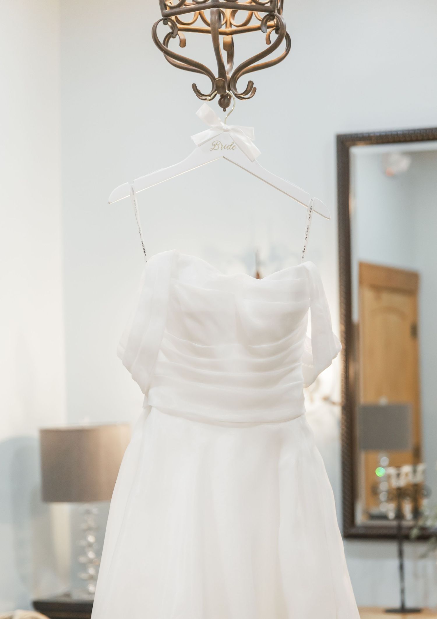 Three elegant white wedding dresses displayed in a row, showing intricate details and strapless designs in a bridal boutique.