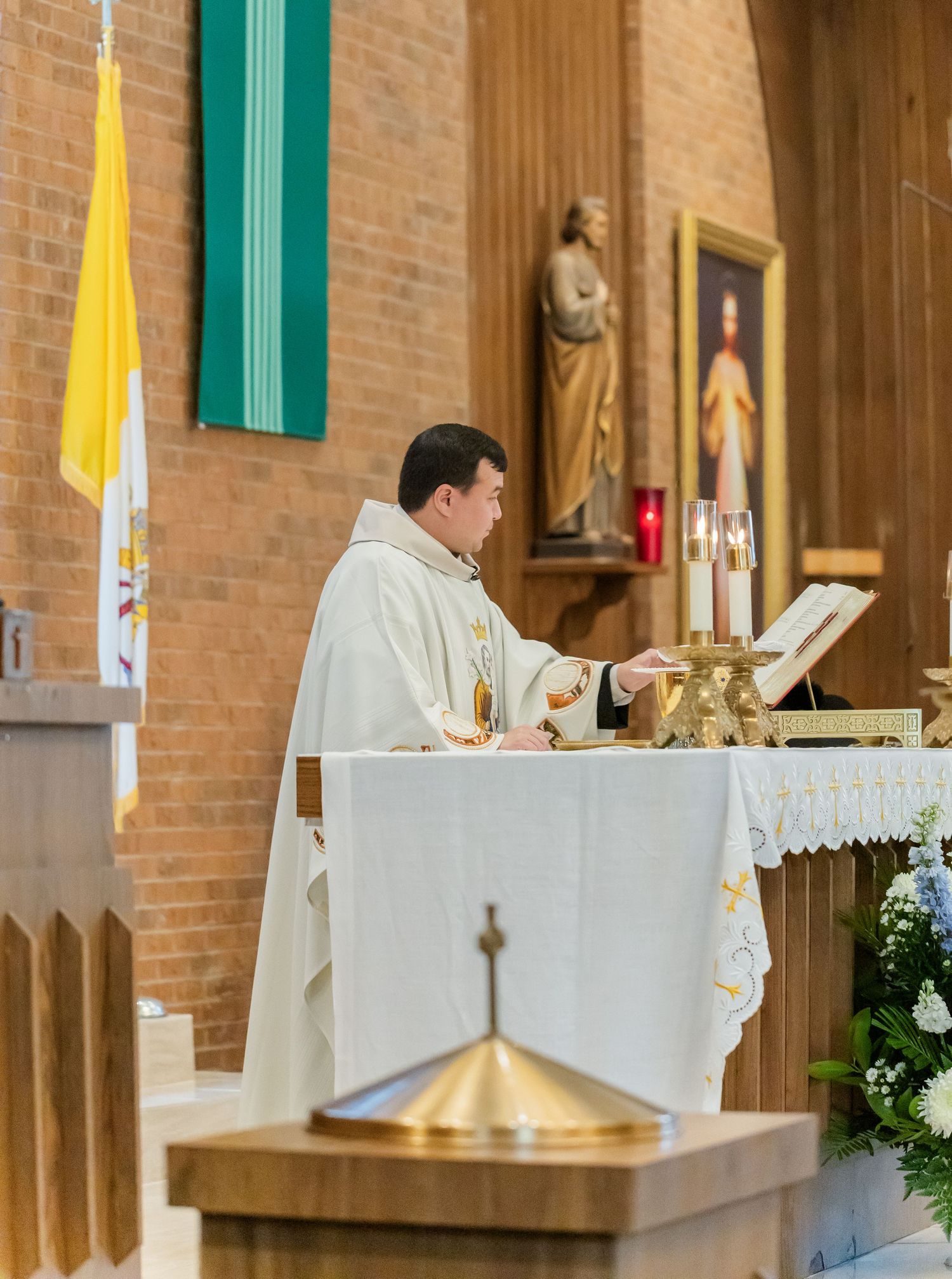 Priest in white robes conducting a Catholic wedding mass at the altar.