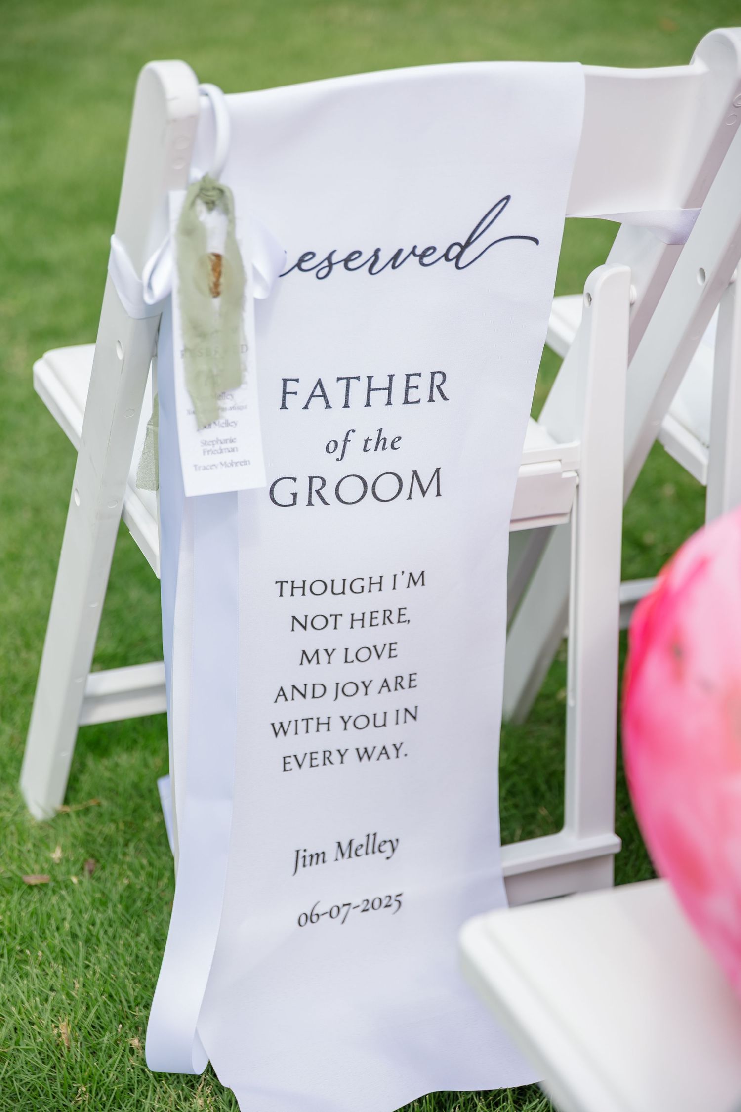White wedding ceremony chairs with memorial signs for loved ones who have passed away displayed on the seats.