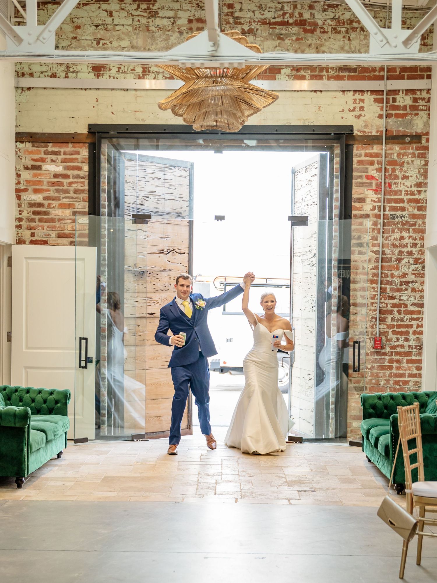 Wedding couple performs a fun dance sequence in an industrial brick-walled venue with emerald green sofas.