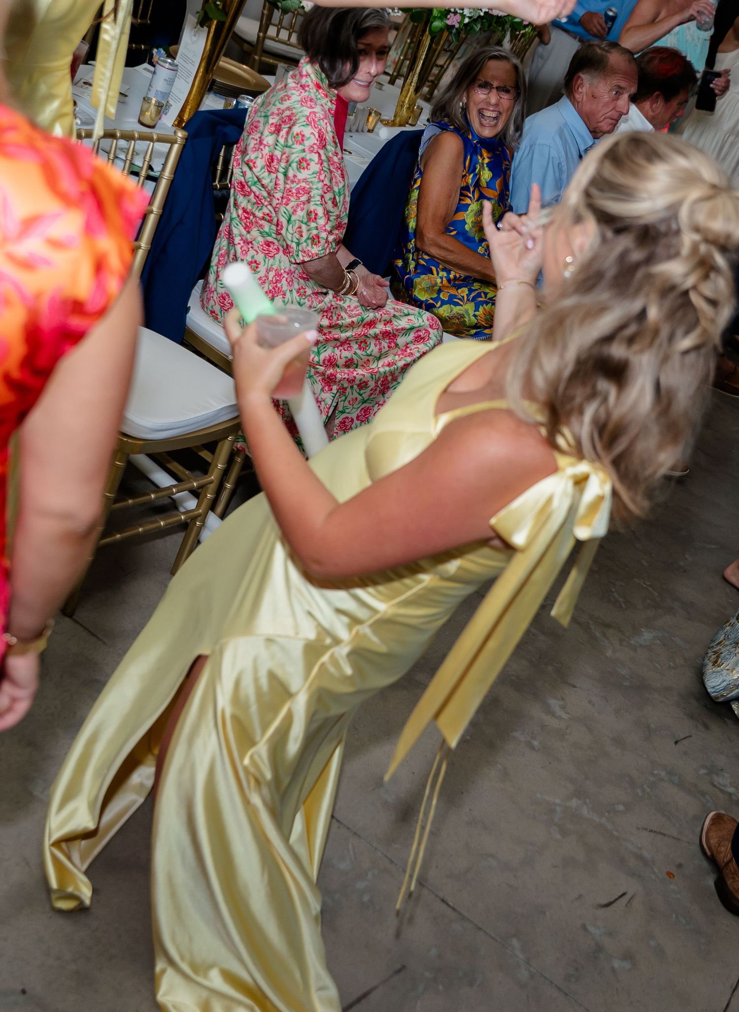 Wedding guests in yellow dresses dancing at a rustic brick venue reception.