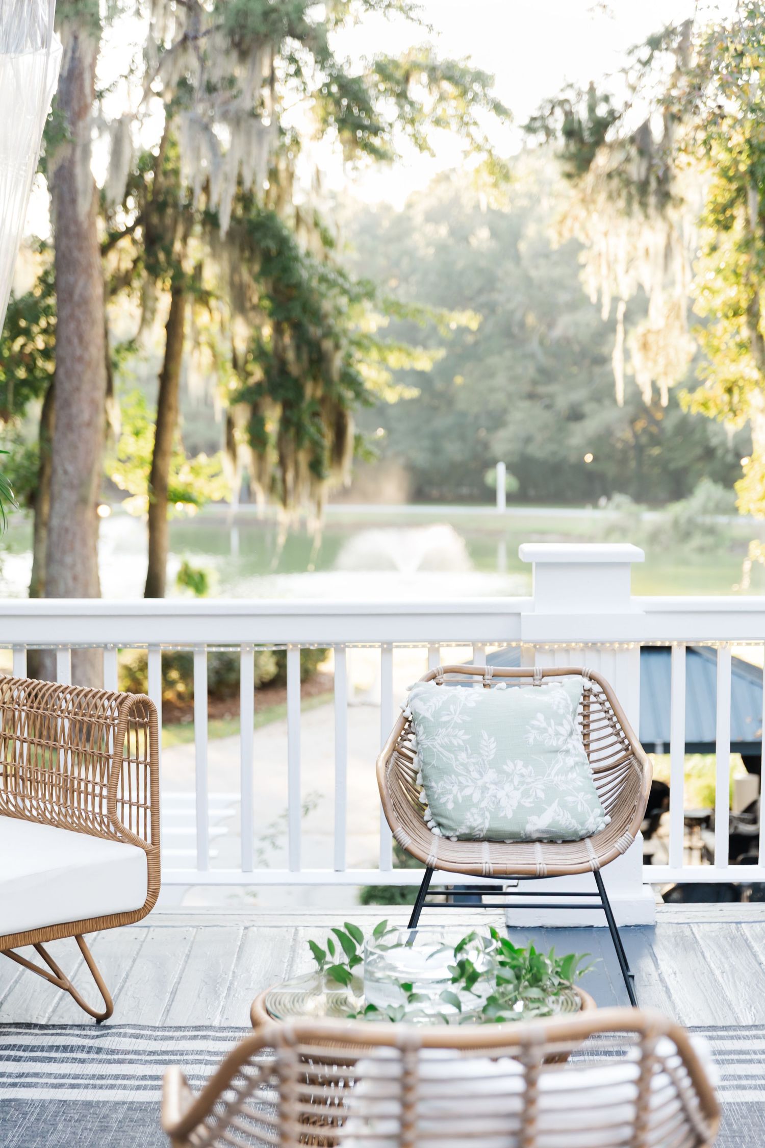 Outdoor wedding venue with white railing deck and woven rattan chairs in natural sunlight.