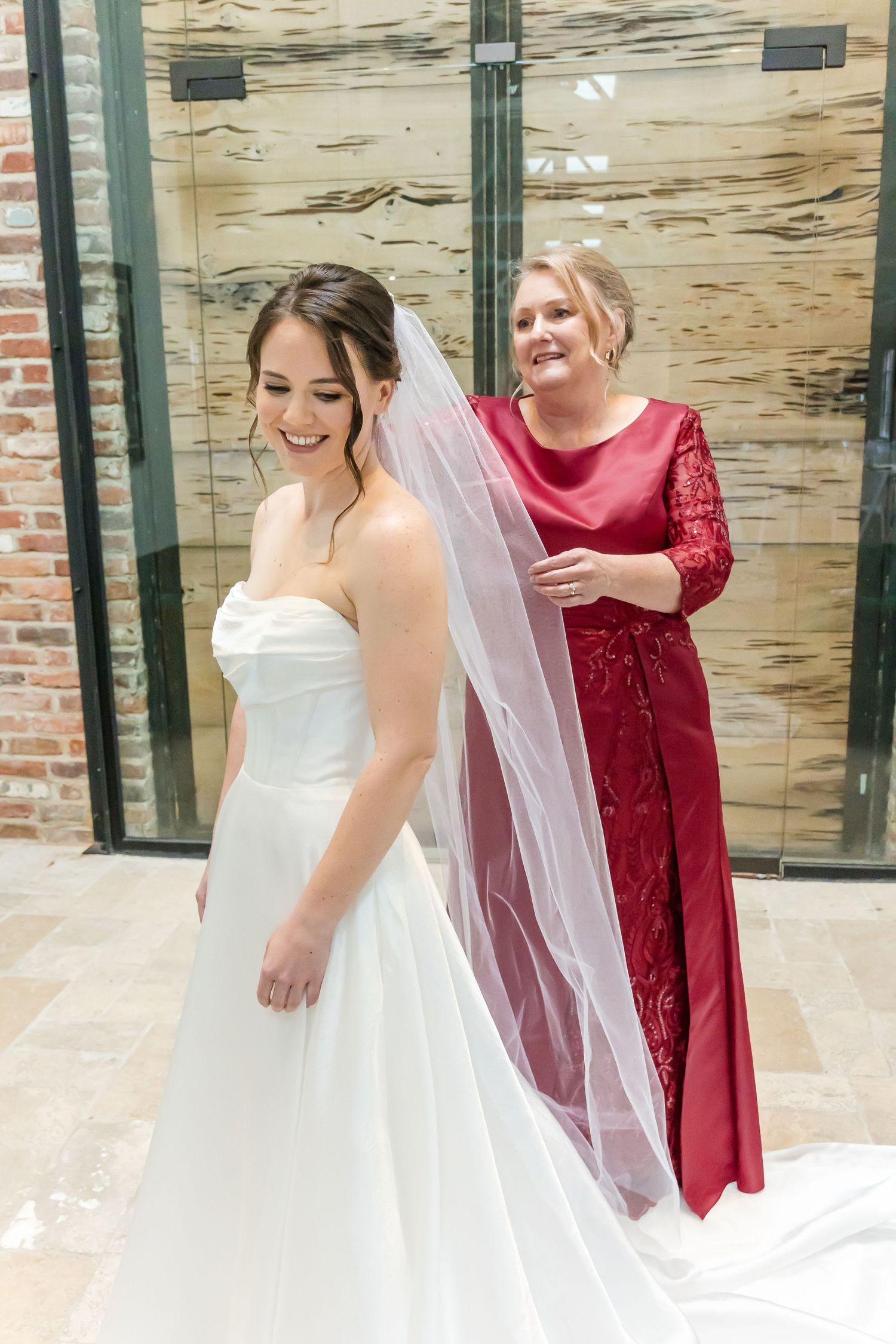 White bridal dress and red bridesmaid gowns with lace details shown in an indoor setting.