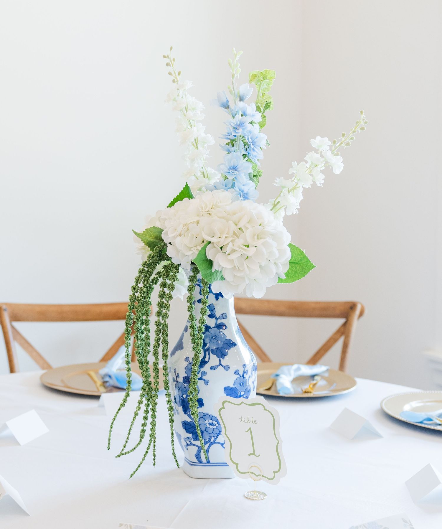Blue and white chinoiserie vase with hydrangeas and delphinium centerpiece on a wedding table.