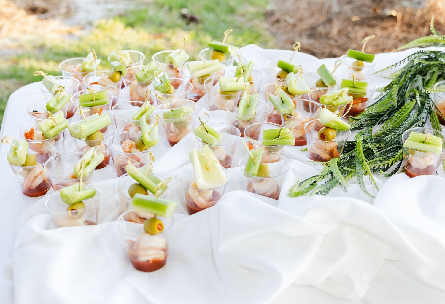 Elegant appetizers arranged in glass cups on white tablecloth for catered event.