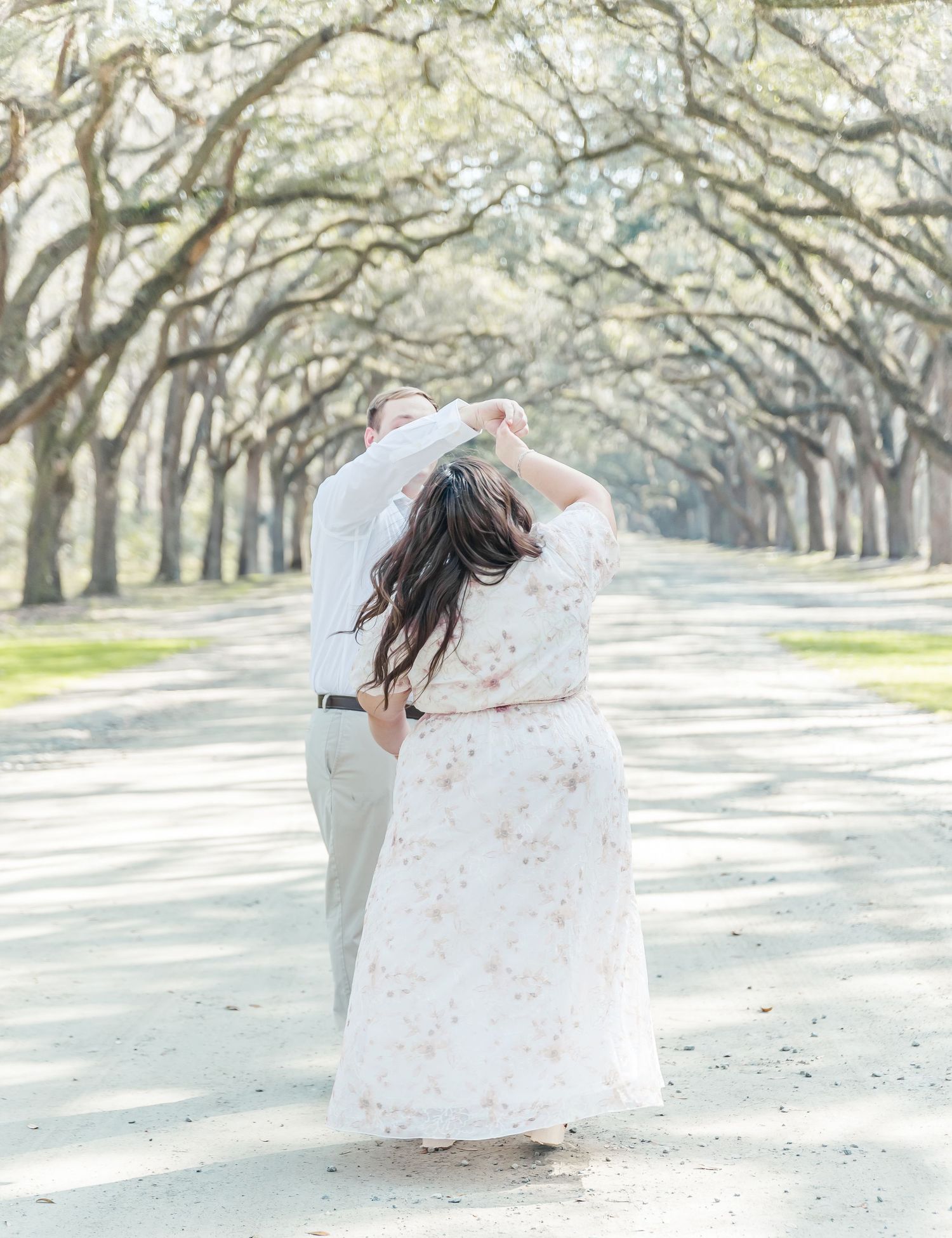 A romantic dance captured from behind under an enchanting oak tree canopy.