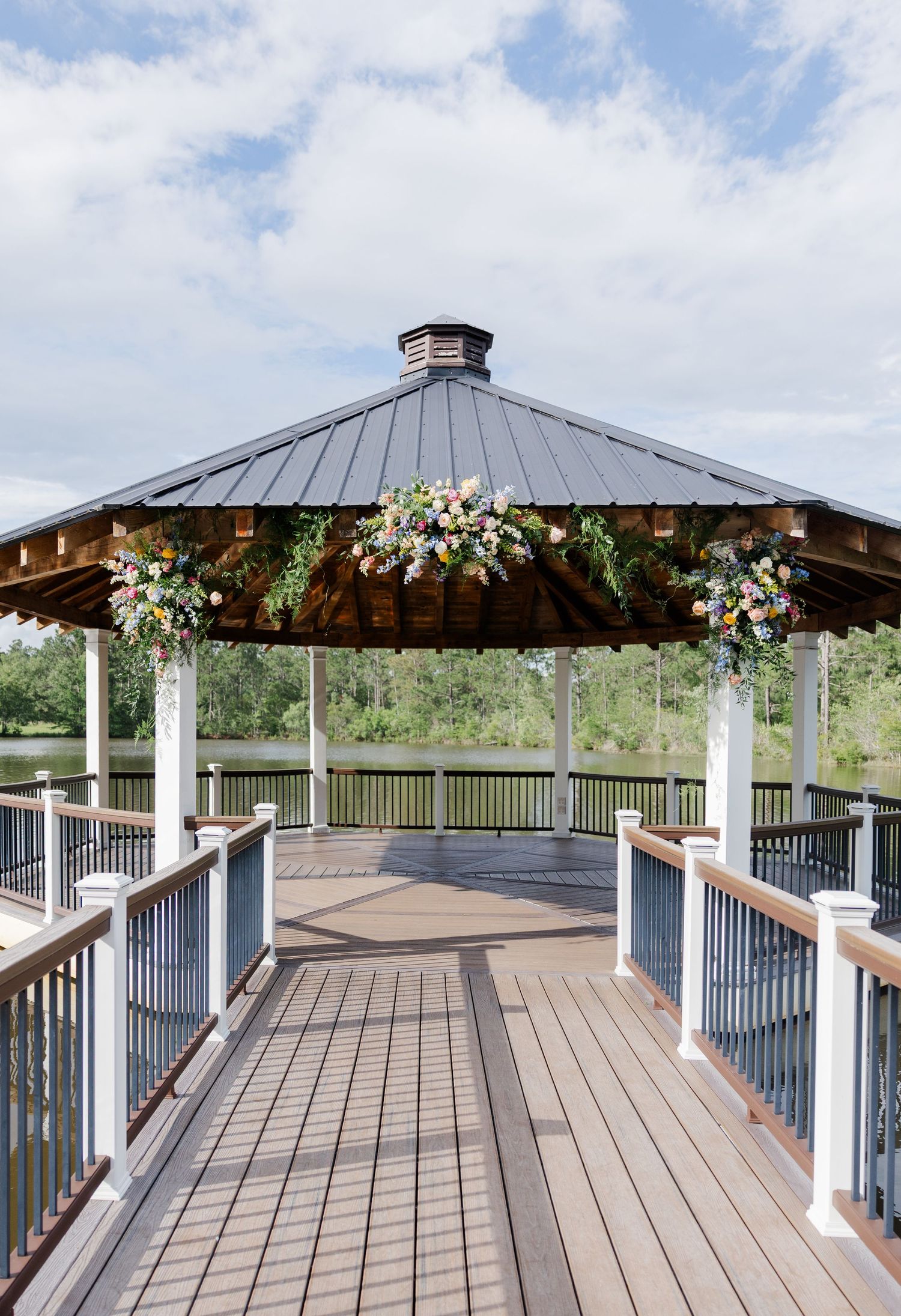 Wooden gazebo decorated with colorful floral arrangements overlooking a scenic outdoor landscape.