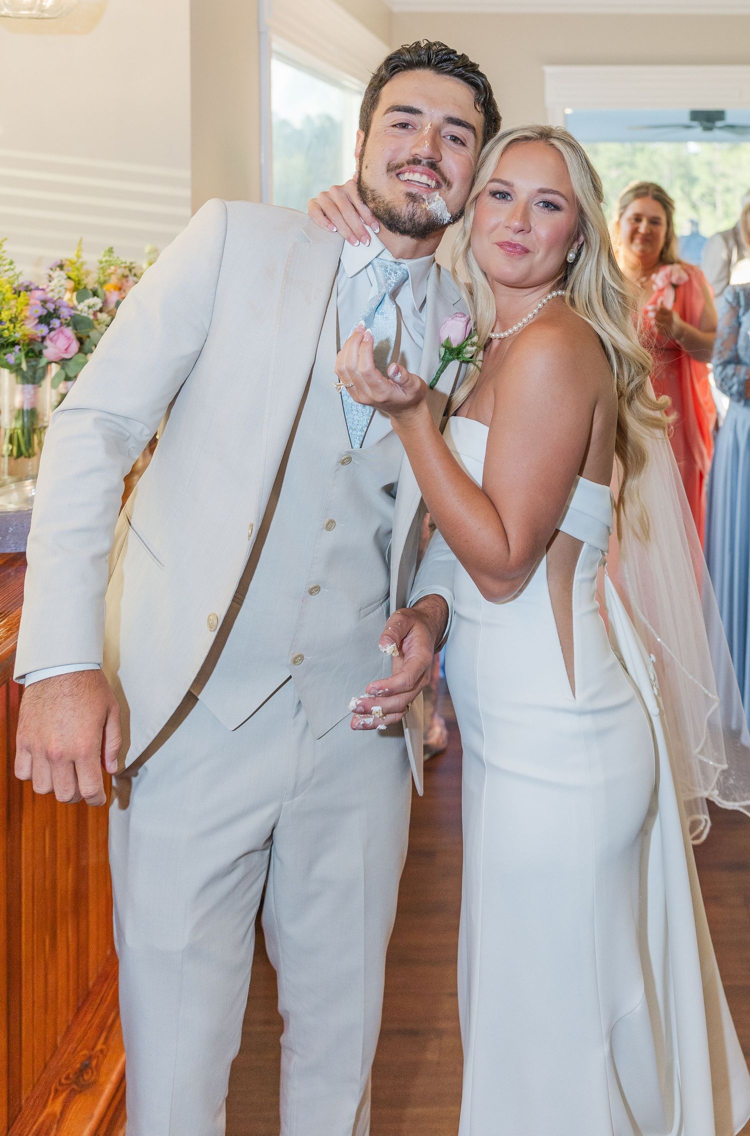 Bride and groom pose playfully together at reception bar after wedding cake cutting ceremony.