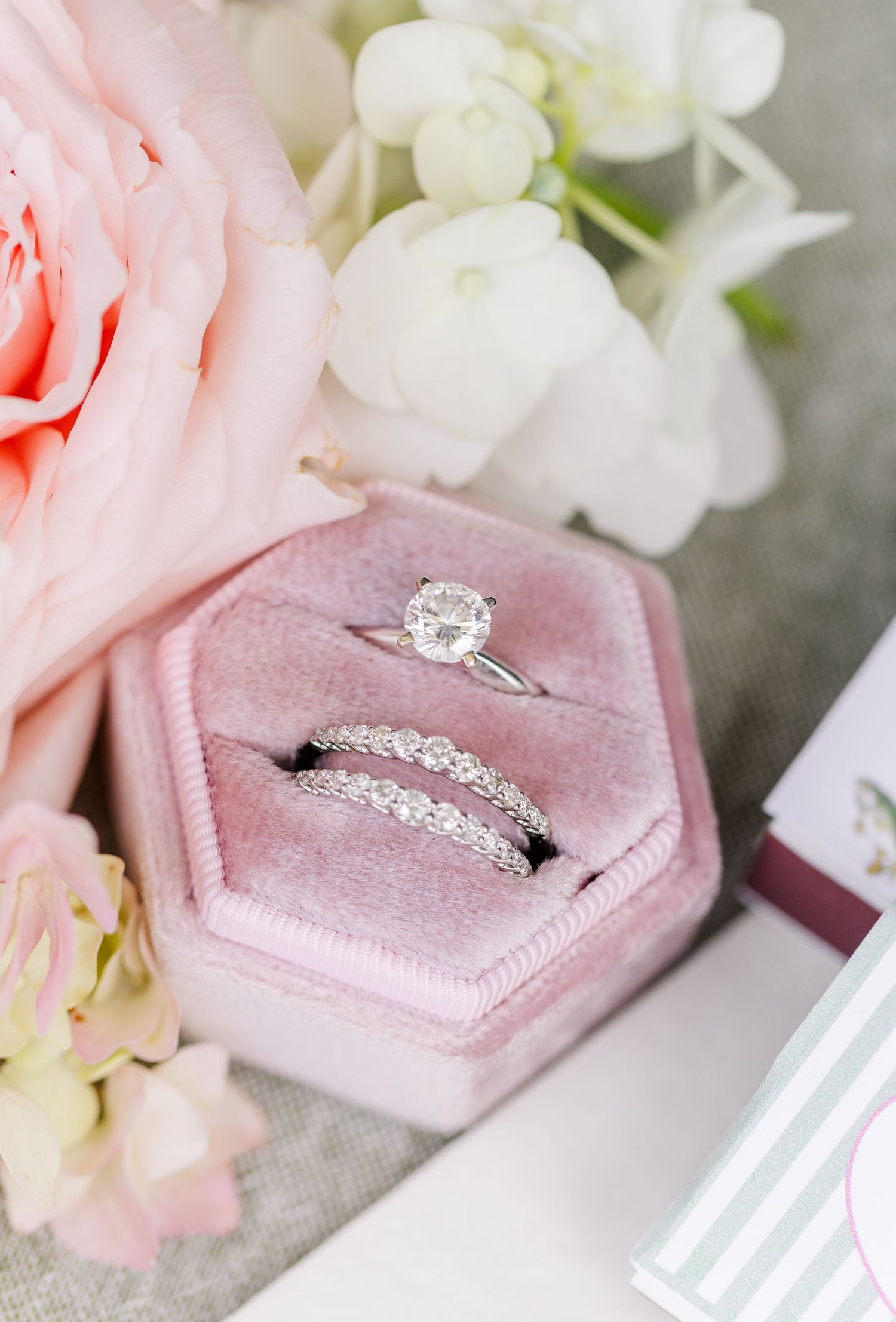 Elegant diamond engagement ring and wedding band set displayed in a pink velvet hexagon ring box.