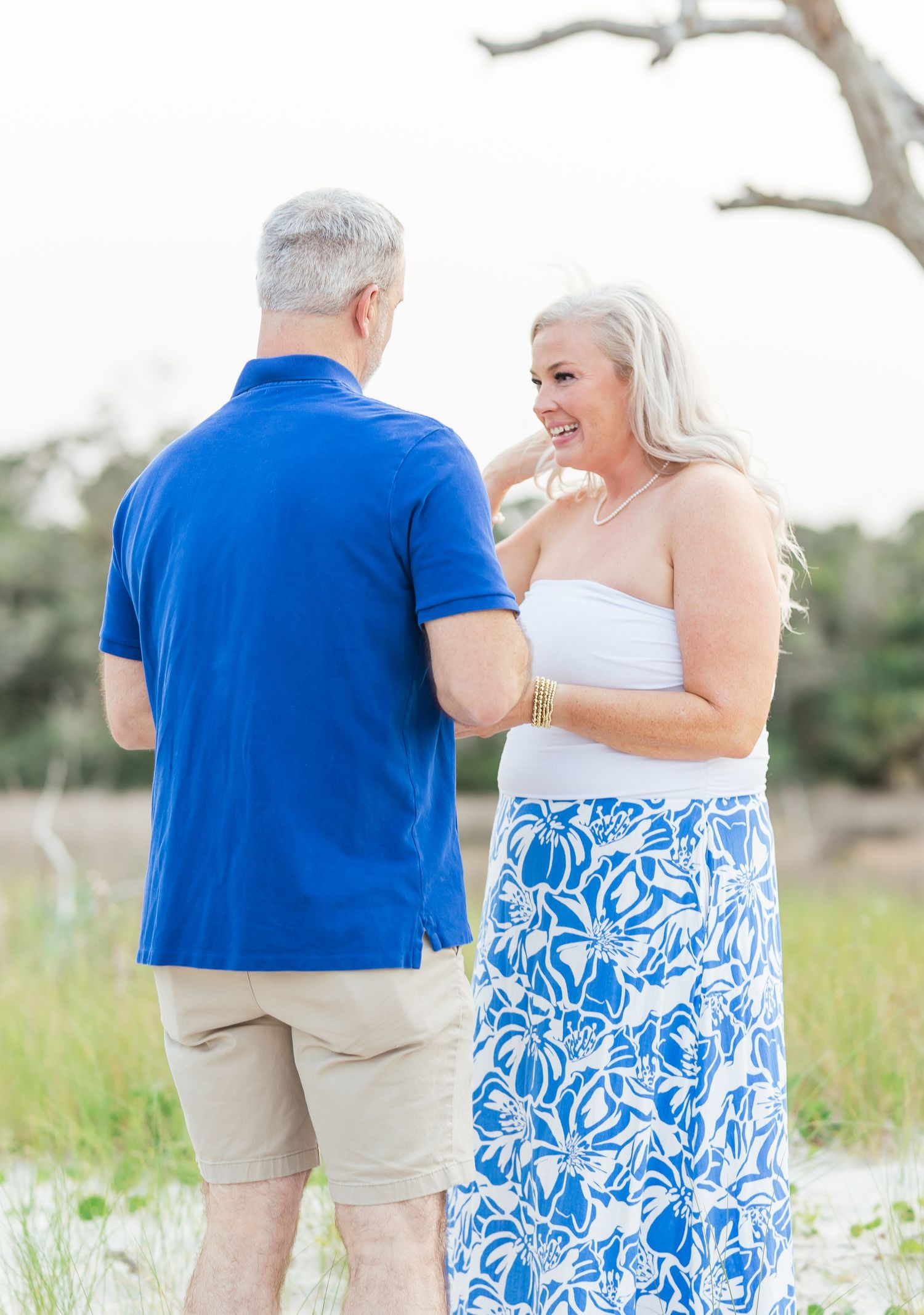 A couple in coordinating blue and white outfits share a tender moment on a beach path.