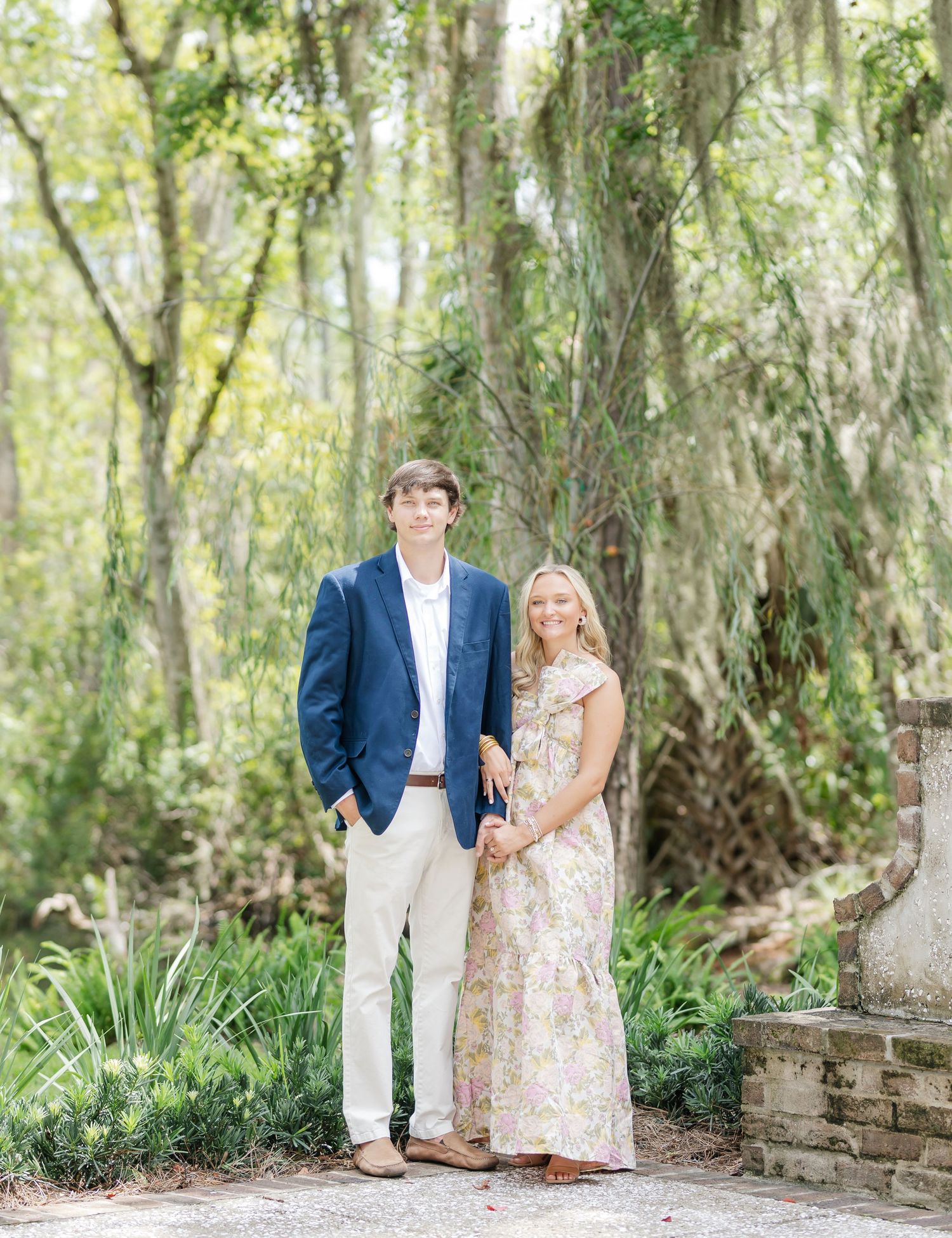 Couple shares romantic moments in a lush garden pathway with Spanish moss draped trees.