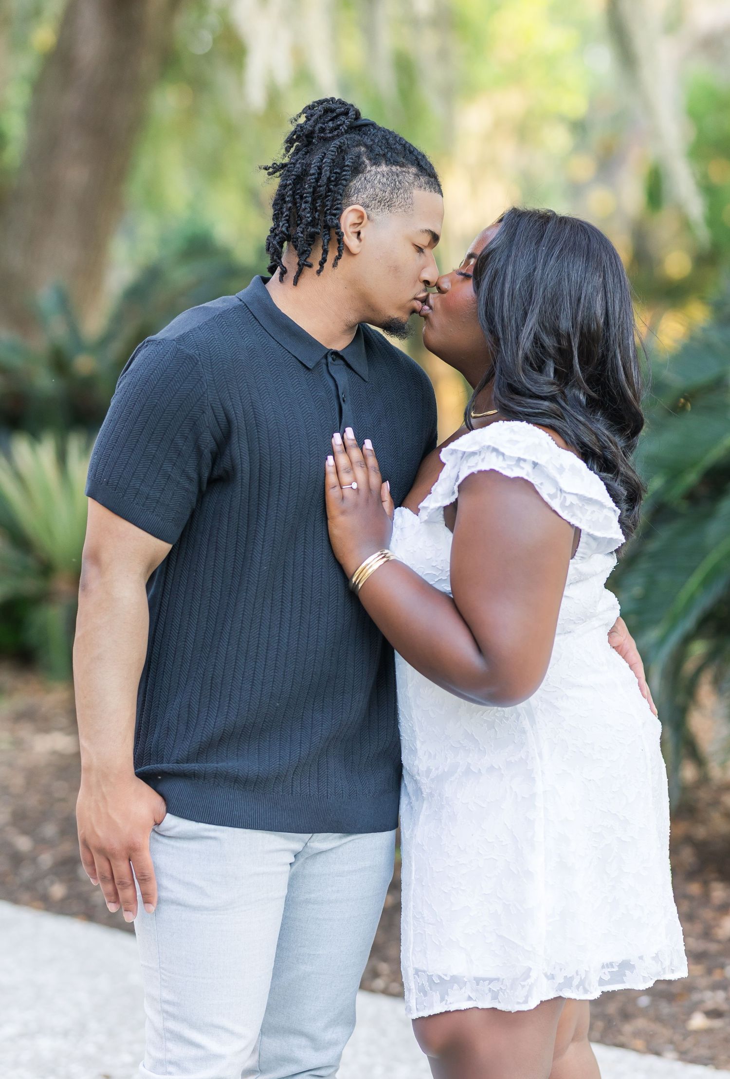 A romantic couple in black and white outfits share tender moments in a garden setting.