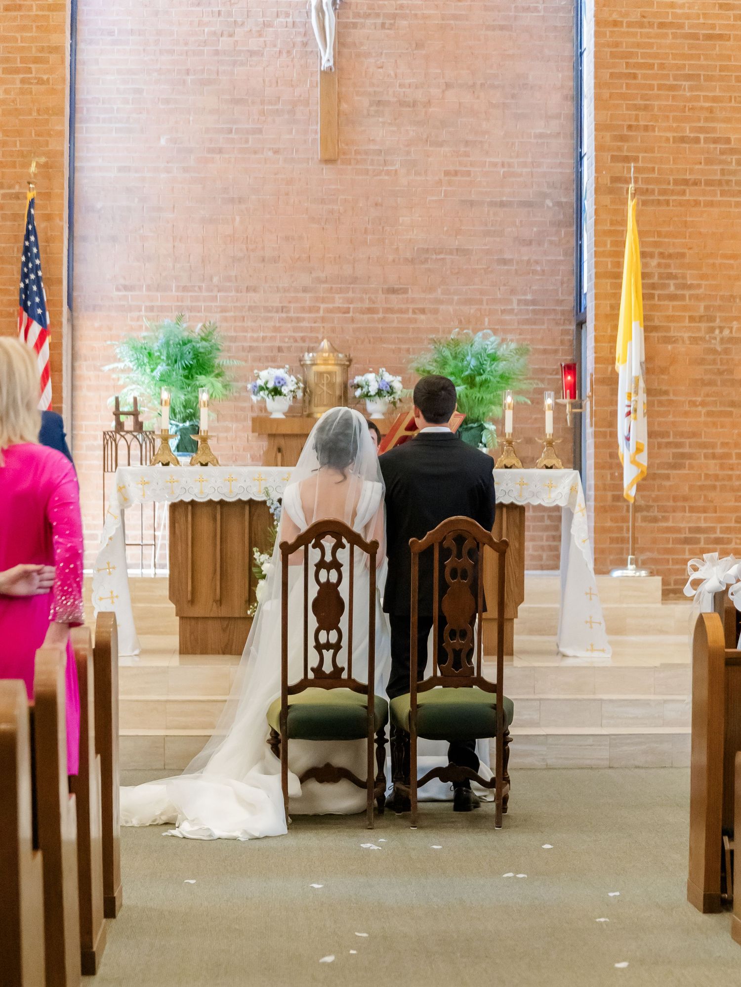 Church sanctuary with brick walls and wooden chairs set up for a wedding ceremony.
