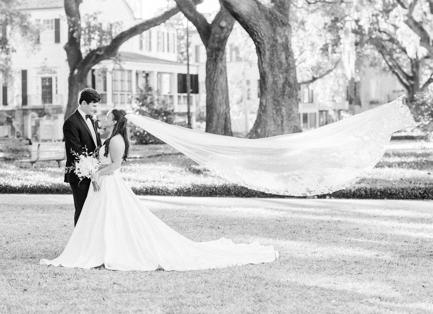 Black and white romantic wedding portrait with bride's veil flowing in the breeze.
