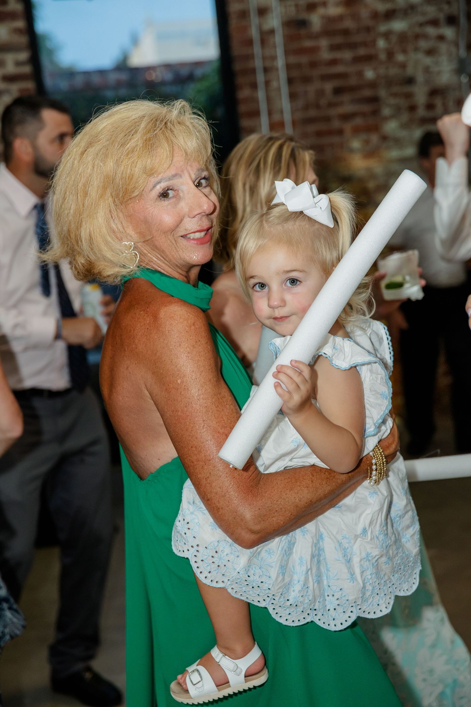 A series of candid dance photos showing a person in green dancing with a small child in a white lacy dress at an event.
