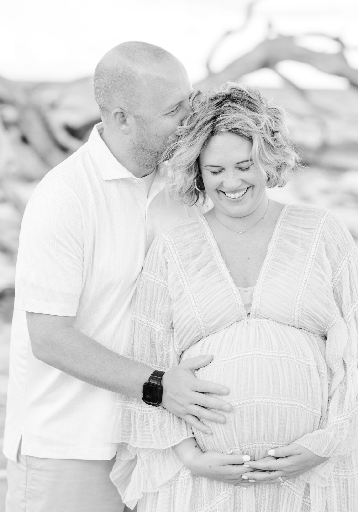 Black and white maternity photos showing intimate moments between couple on beach.