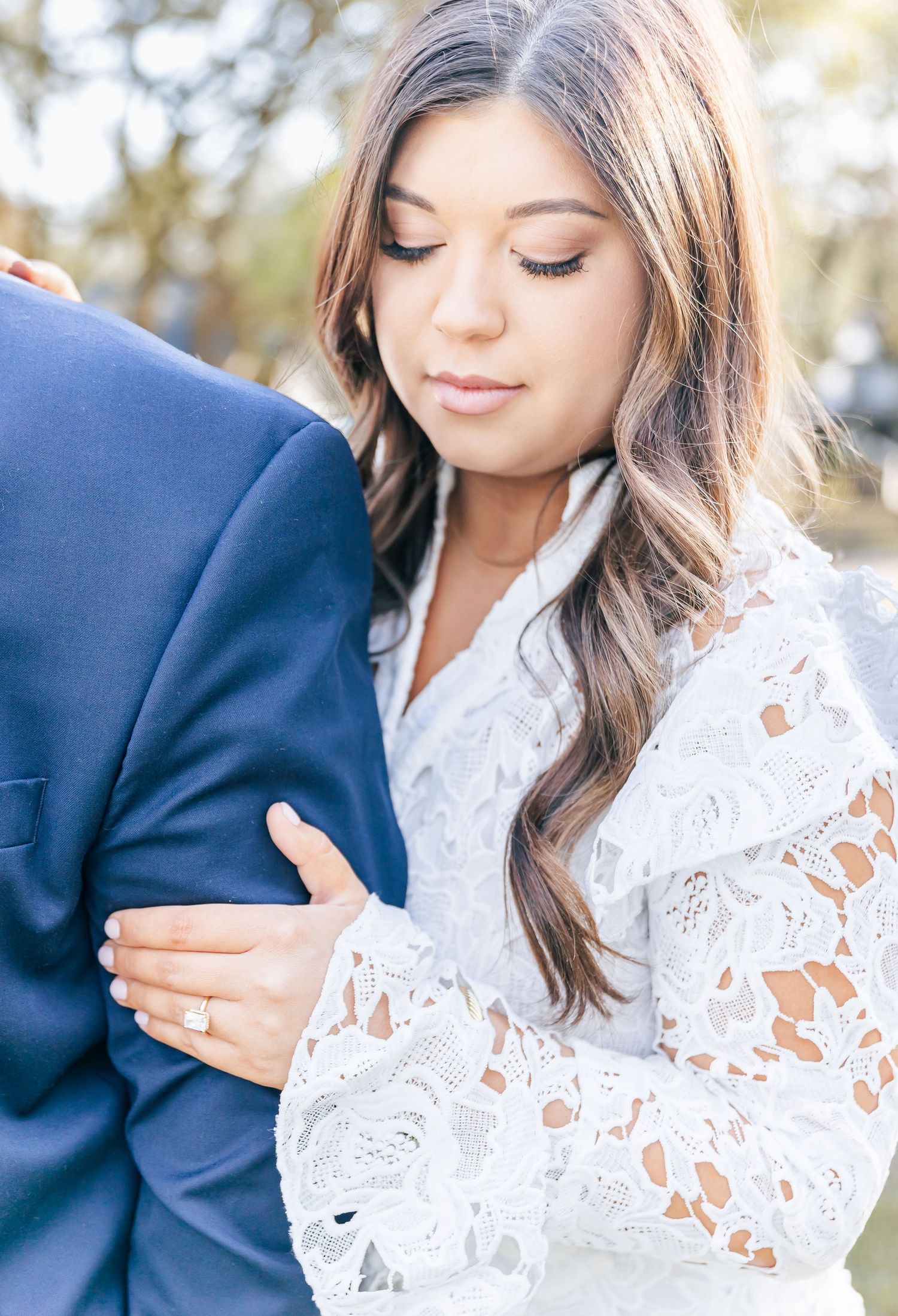 Close-up photo showing delicate lace sleeves and an engagement ring.