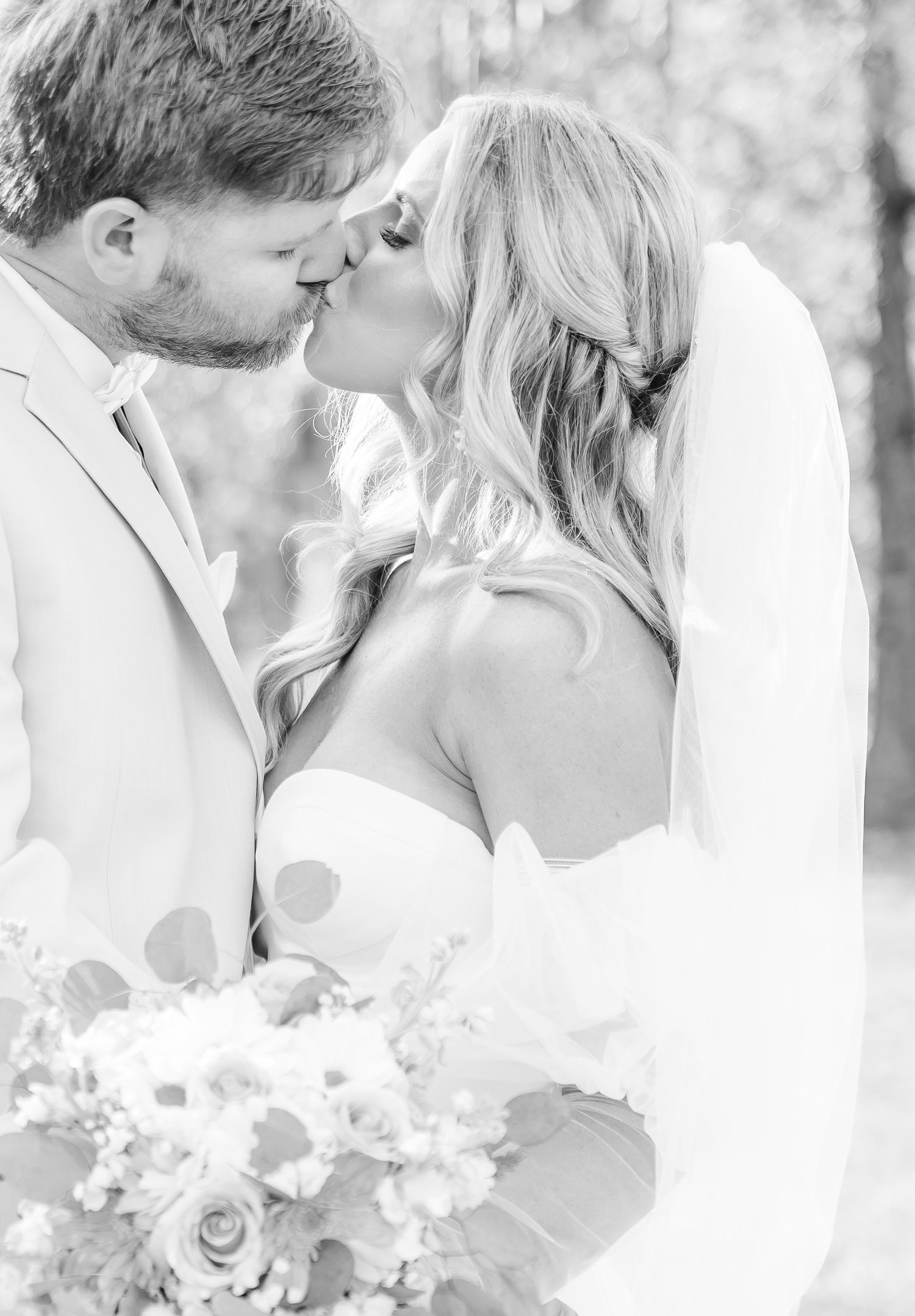 A romantic black and white photo of a couple sharing their first kiss as newlyweds.