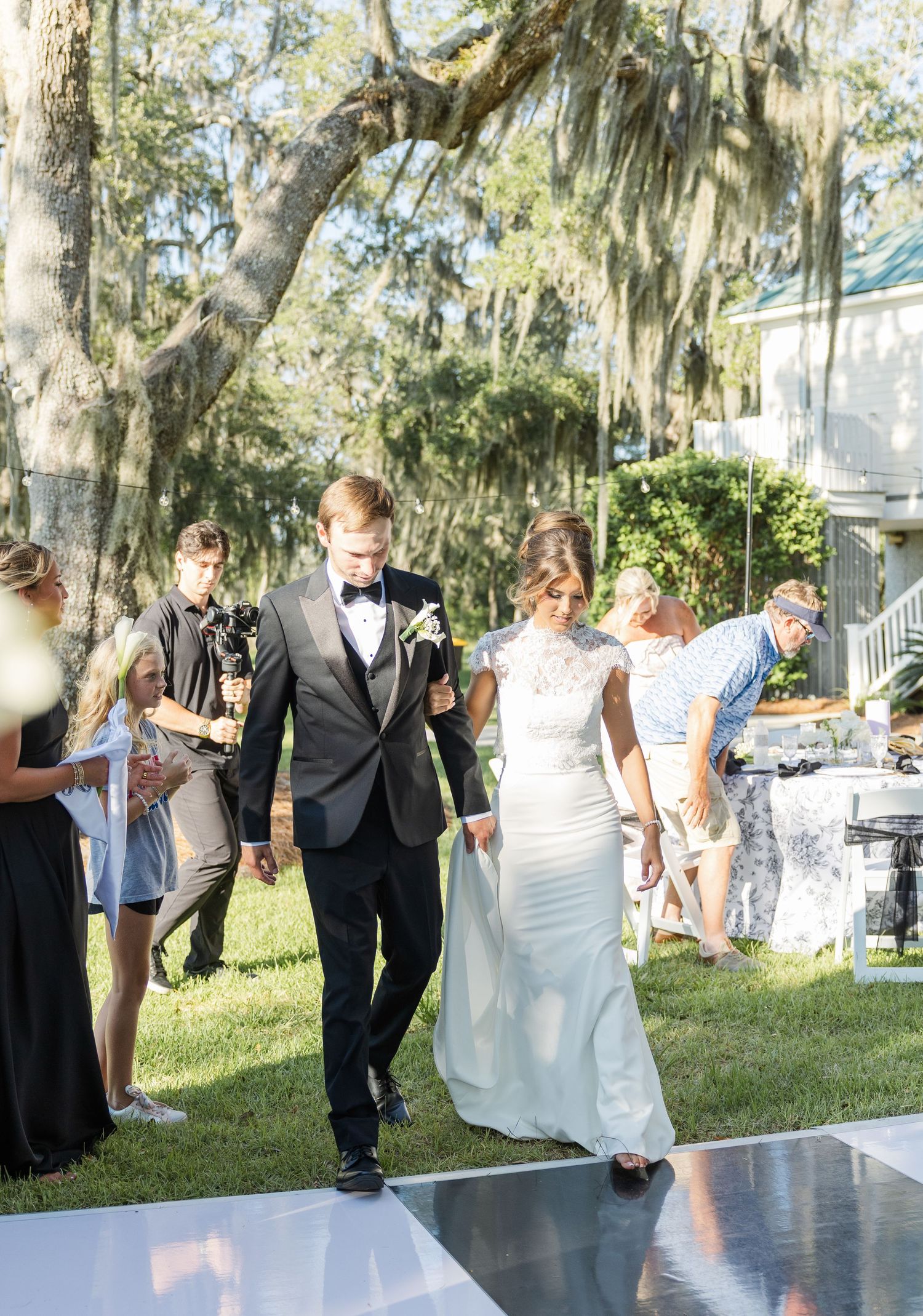 Bride and groom walk hand-in-hand down the aisle at an elegant outdoor wedding ceremony.