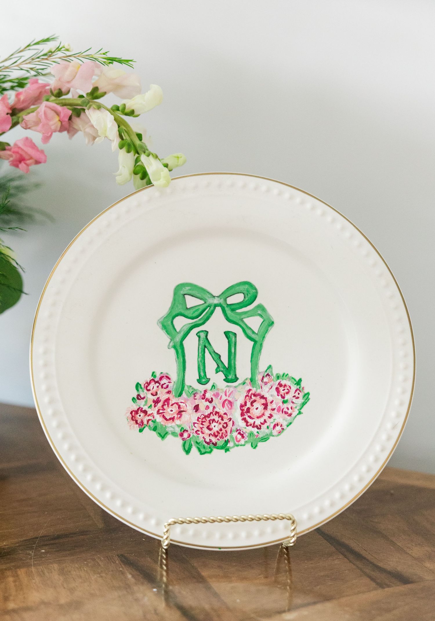 Hand-painted monogram wedding plate with letter N, green bow, and pink floral design on white china.