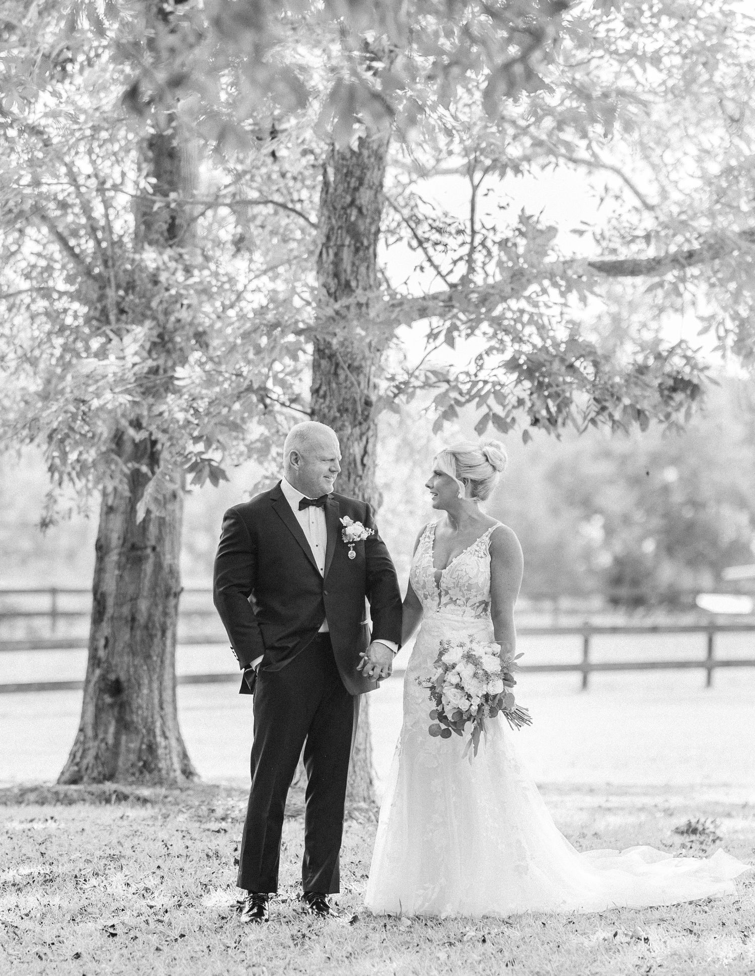 A series of romantic black and white wedding photos showing a couple sharing intimate moments under large trees.