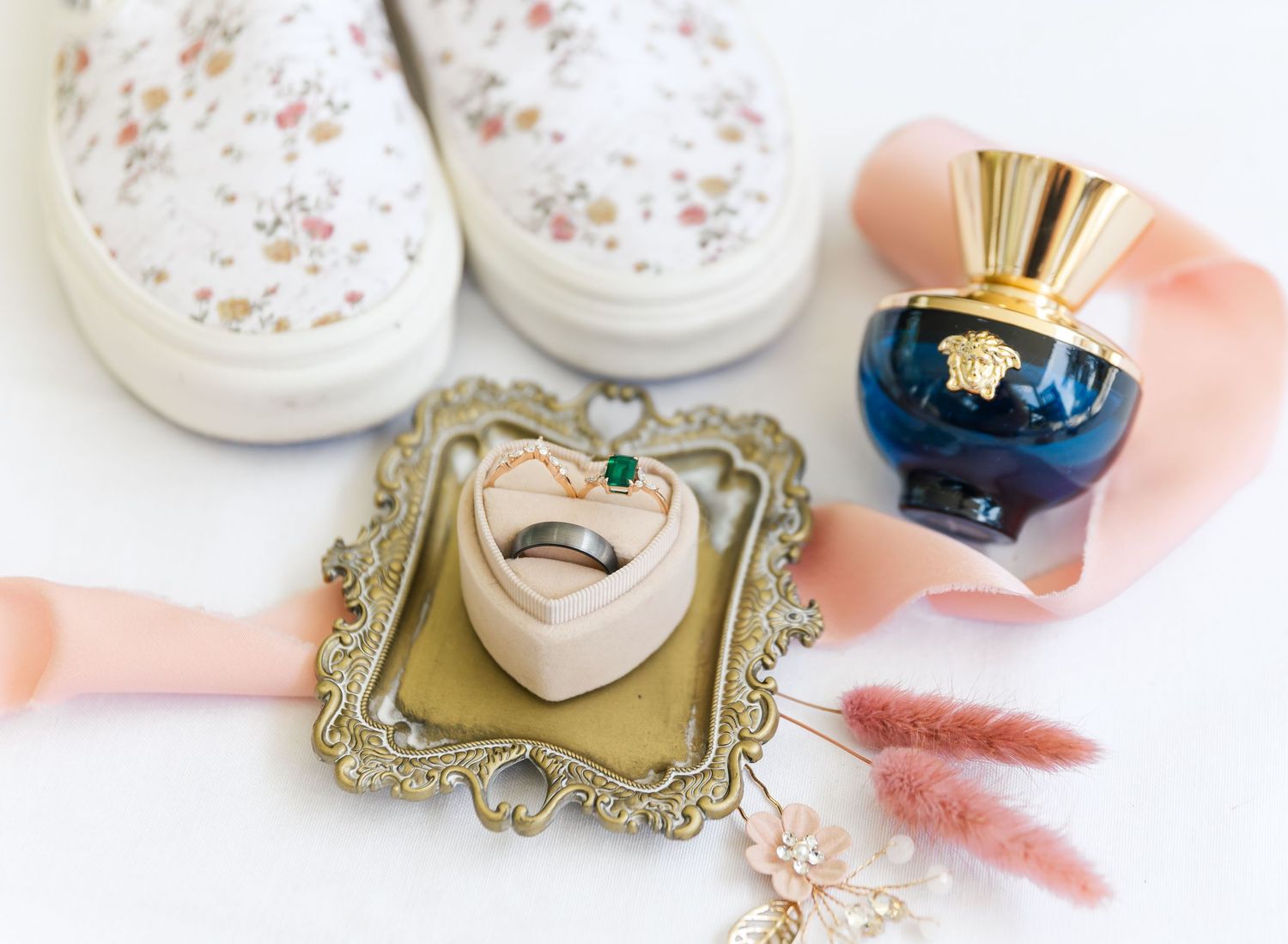 Flat lay of beauty products with white jars, gold mirror, and pink ribbon on light background.
