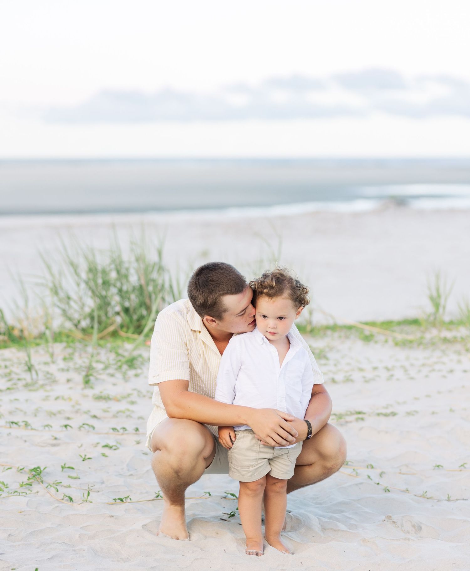 A tender beachside moment captured against a cloudy coastal backdrop.