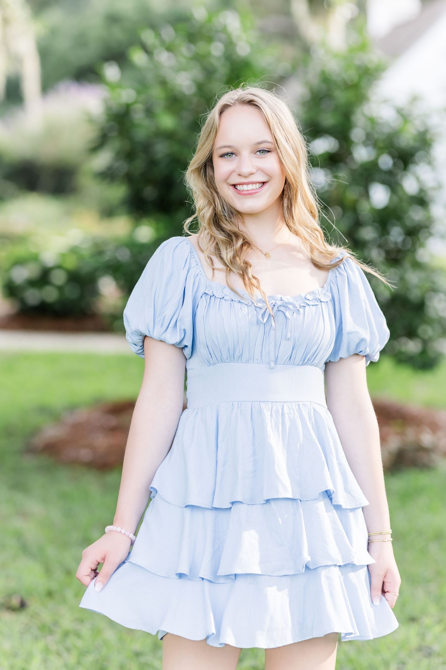 A tiered light blue dress with puff sleeves and empire waist styled for a spring garden photoshoot.
