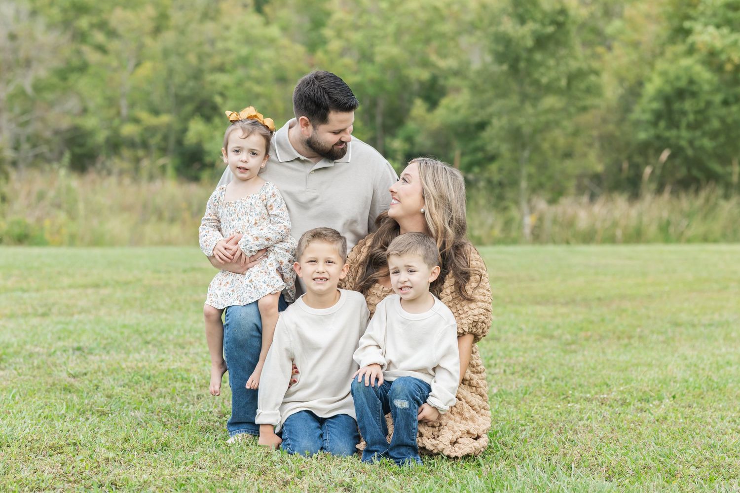 A family sits together on grass in a park during a sunny autumn day.