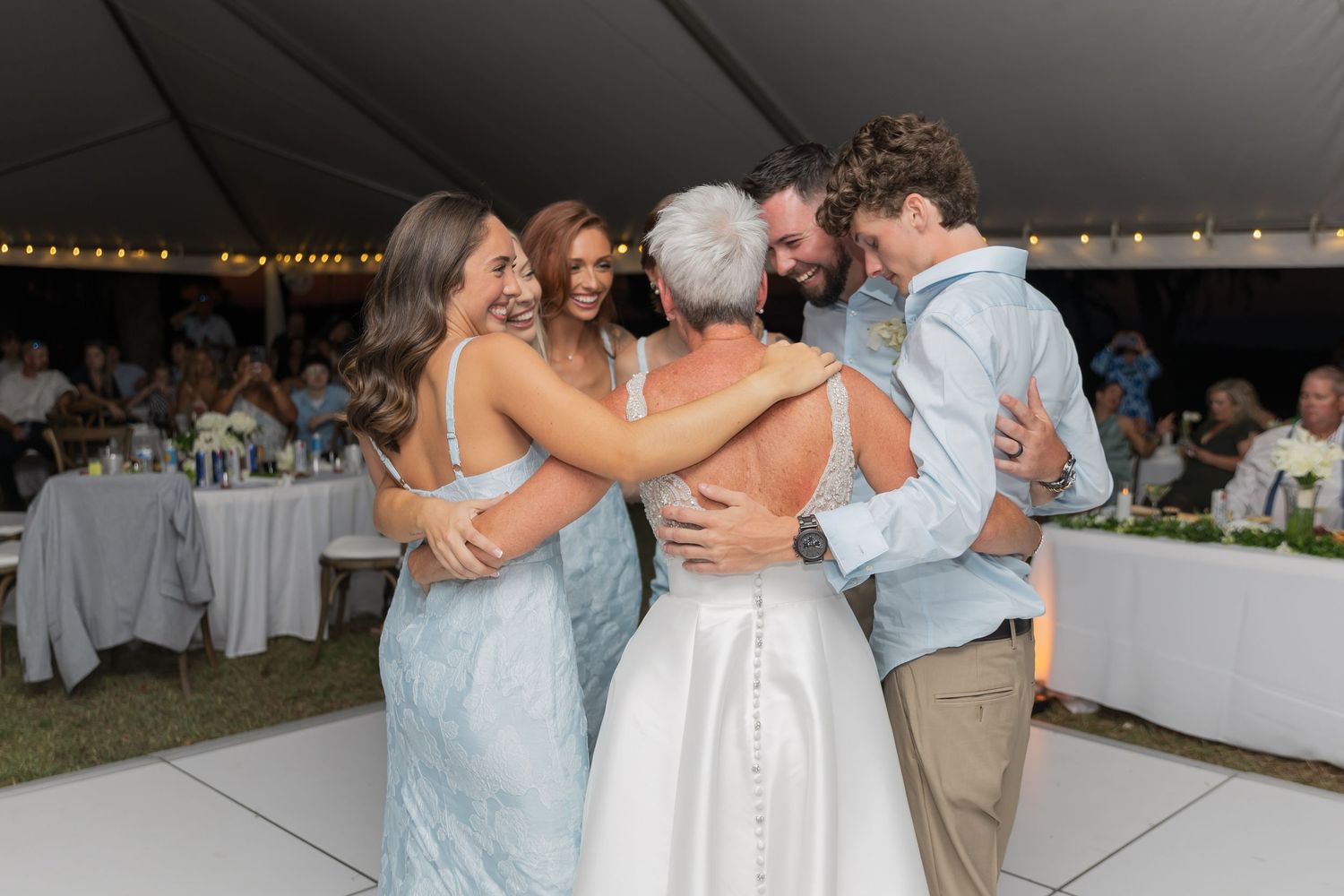Wedding party members dance and celebrate at an evening outdoor reception.