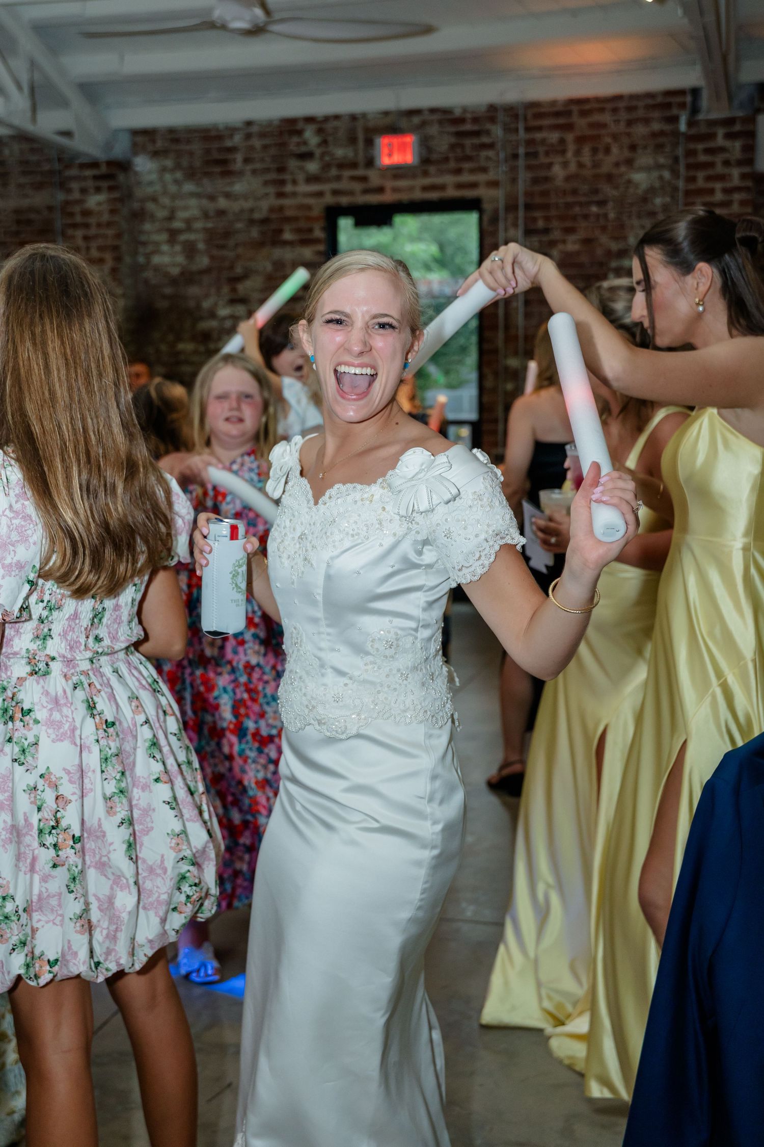 Wedding celebration with dancers in floral dresses and white gowns enjoying a lively party.