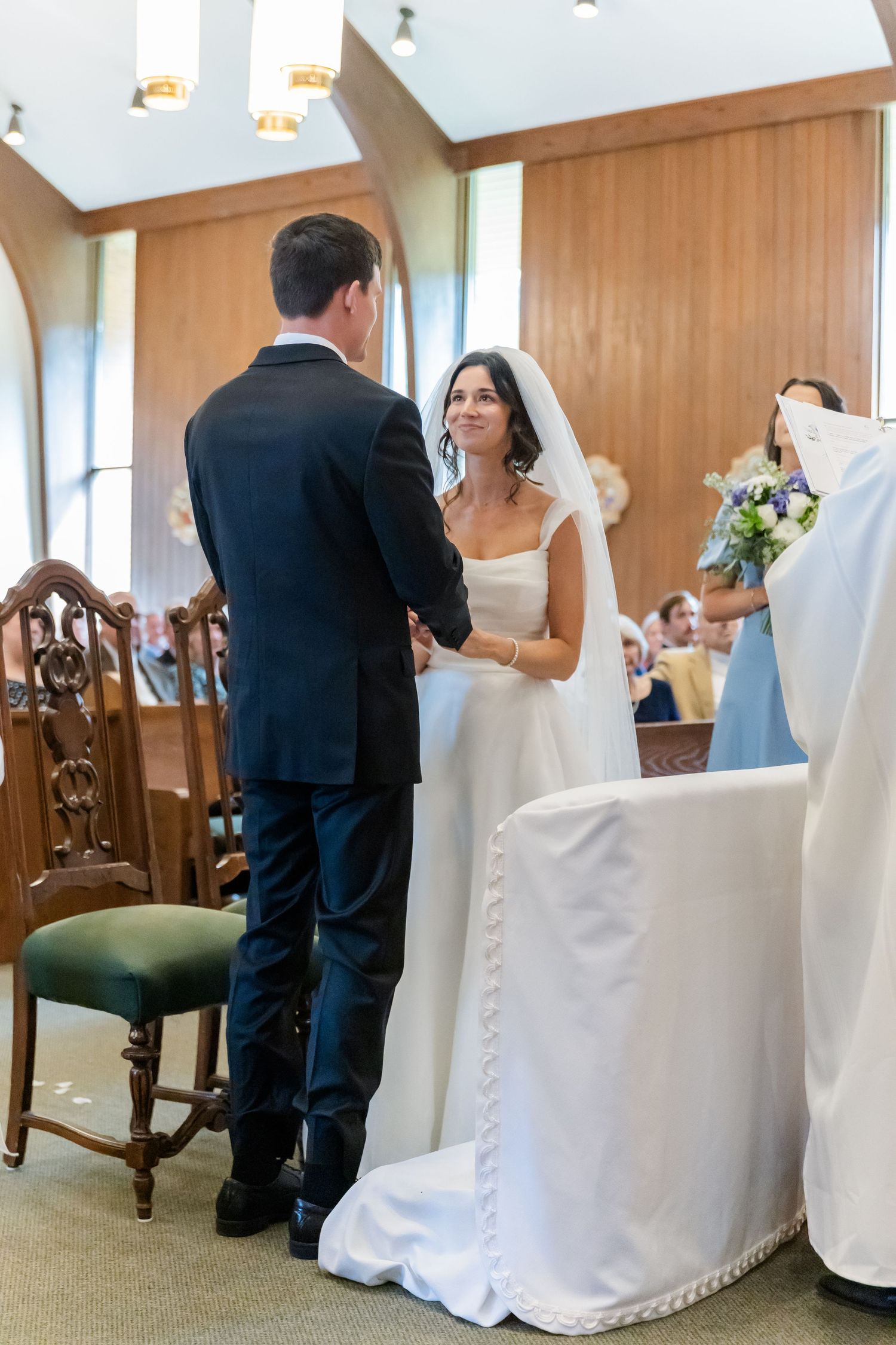Wedding ceremony seating with white chair covers in a church setting.