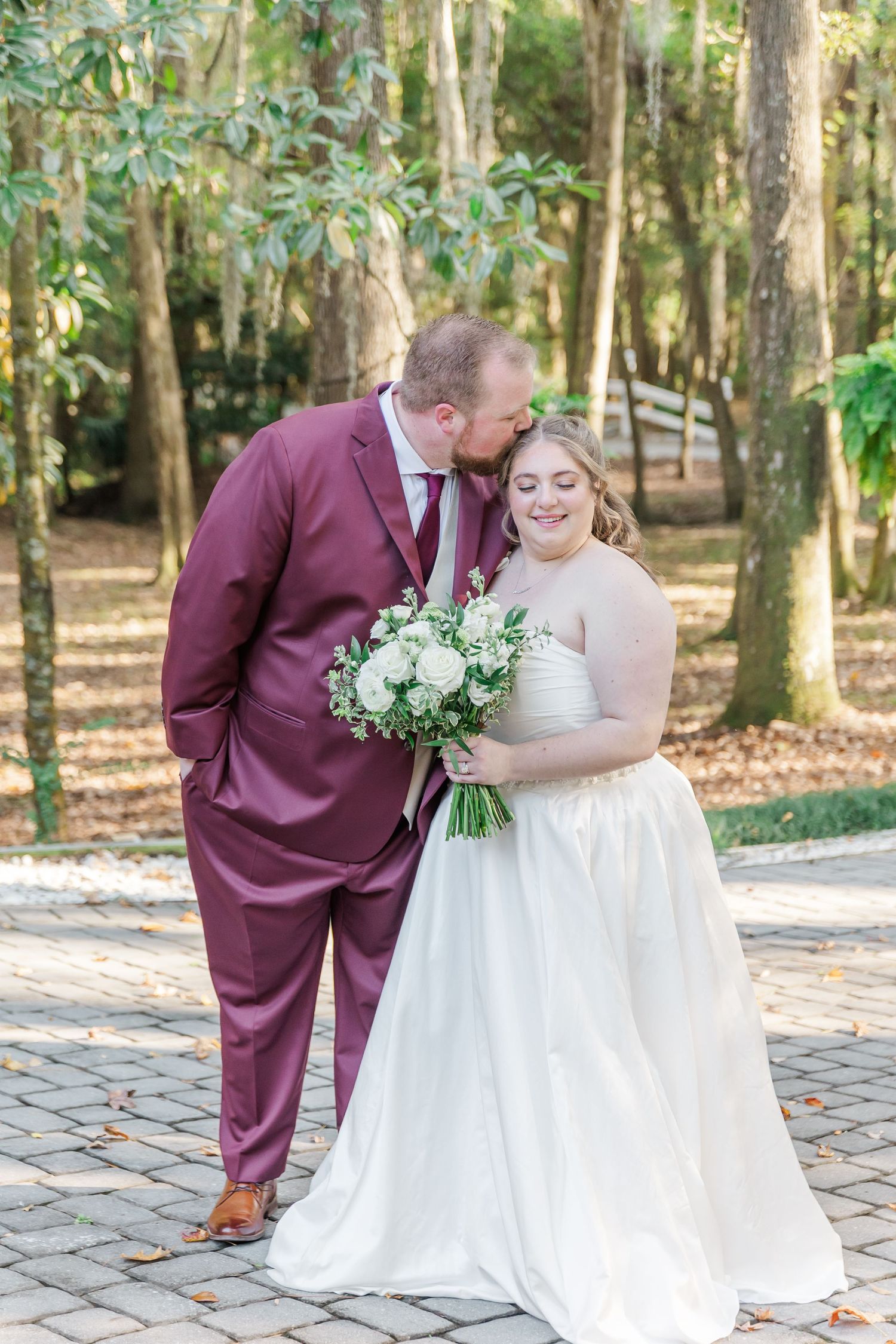 A couple shares intimate wedding moments on a stone patio surrounded by lush woodland.