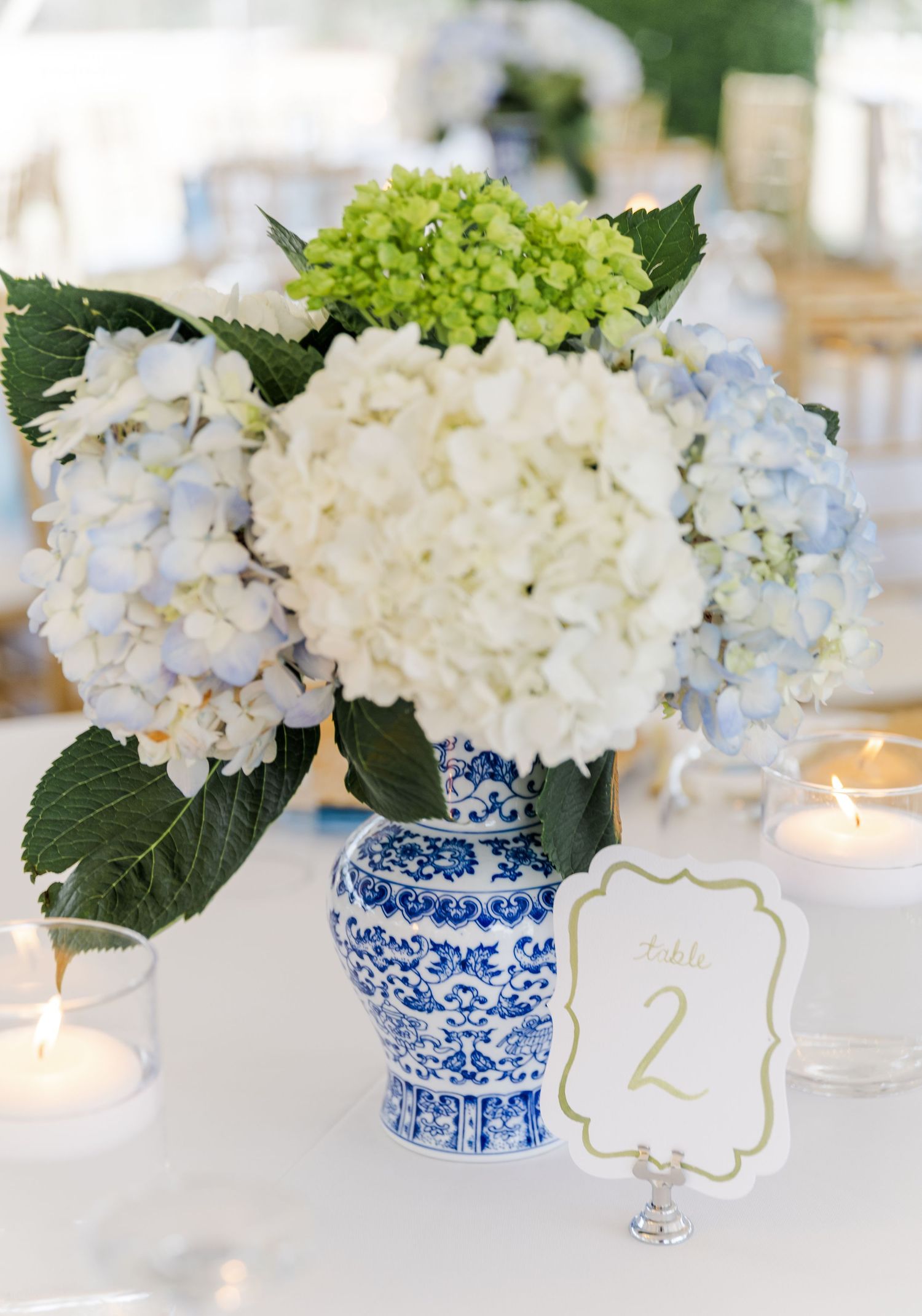 Blue and white ginger jar vase filled with white and green hydrangeas beside a Table 2 sign.