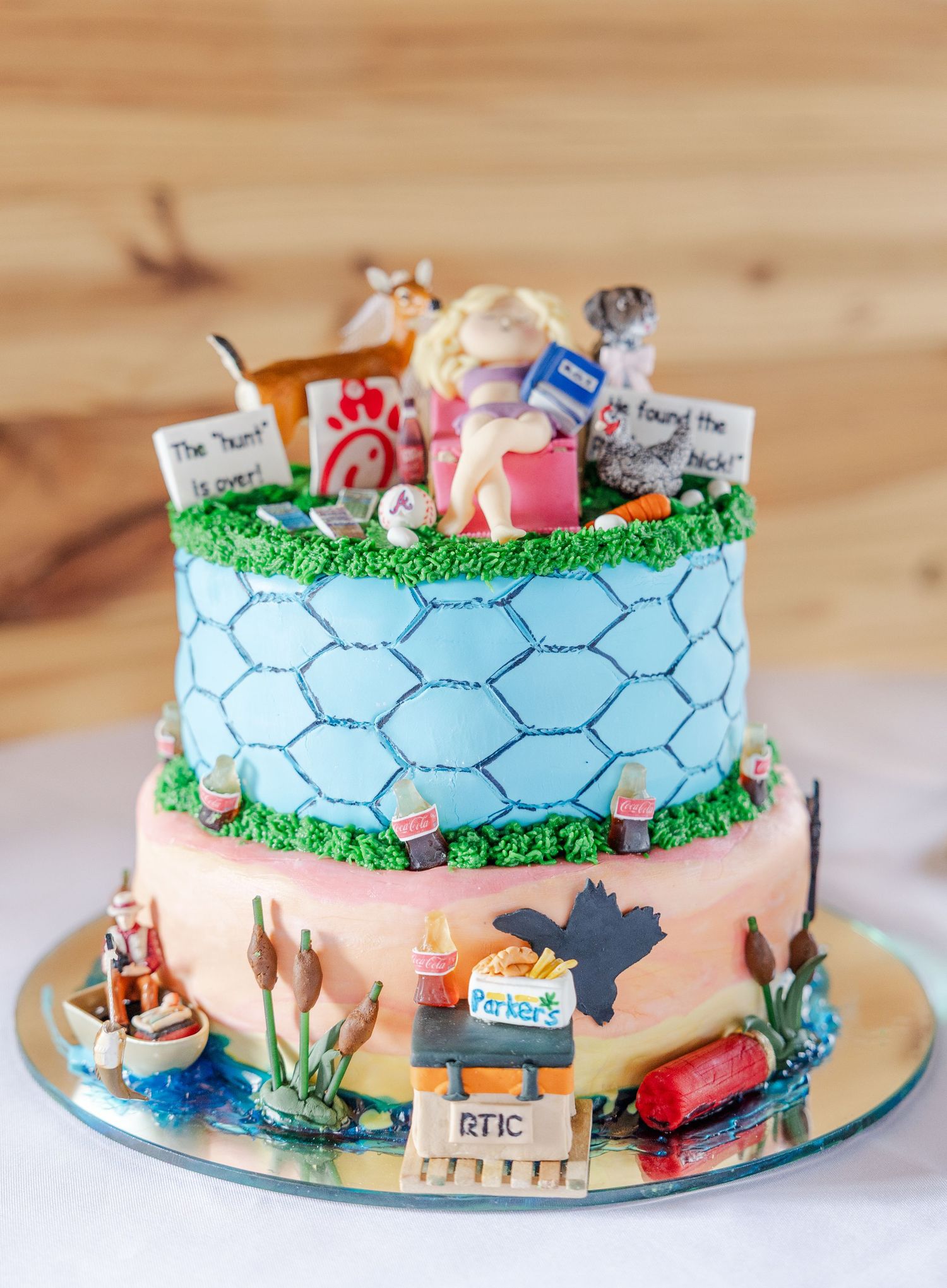Colorful two-tier groom's cake decorated with personalized fondant figures and brand logos.