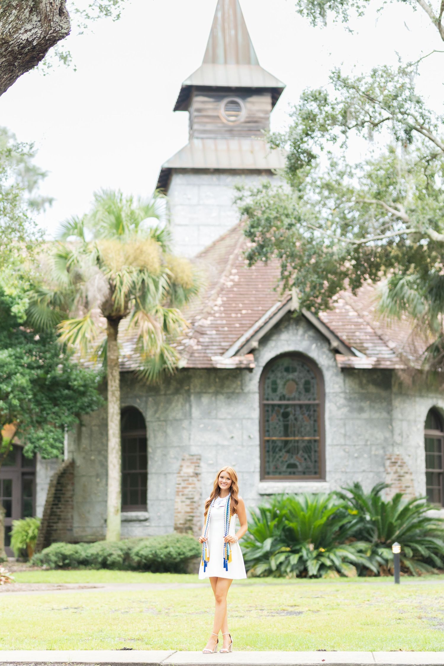 Stone church with arched windows and palm trees in a lush garden setting creates a serene historic atmosphere.