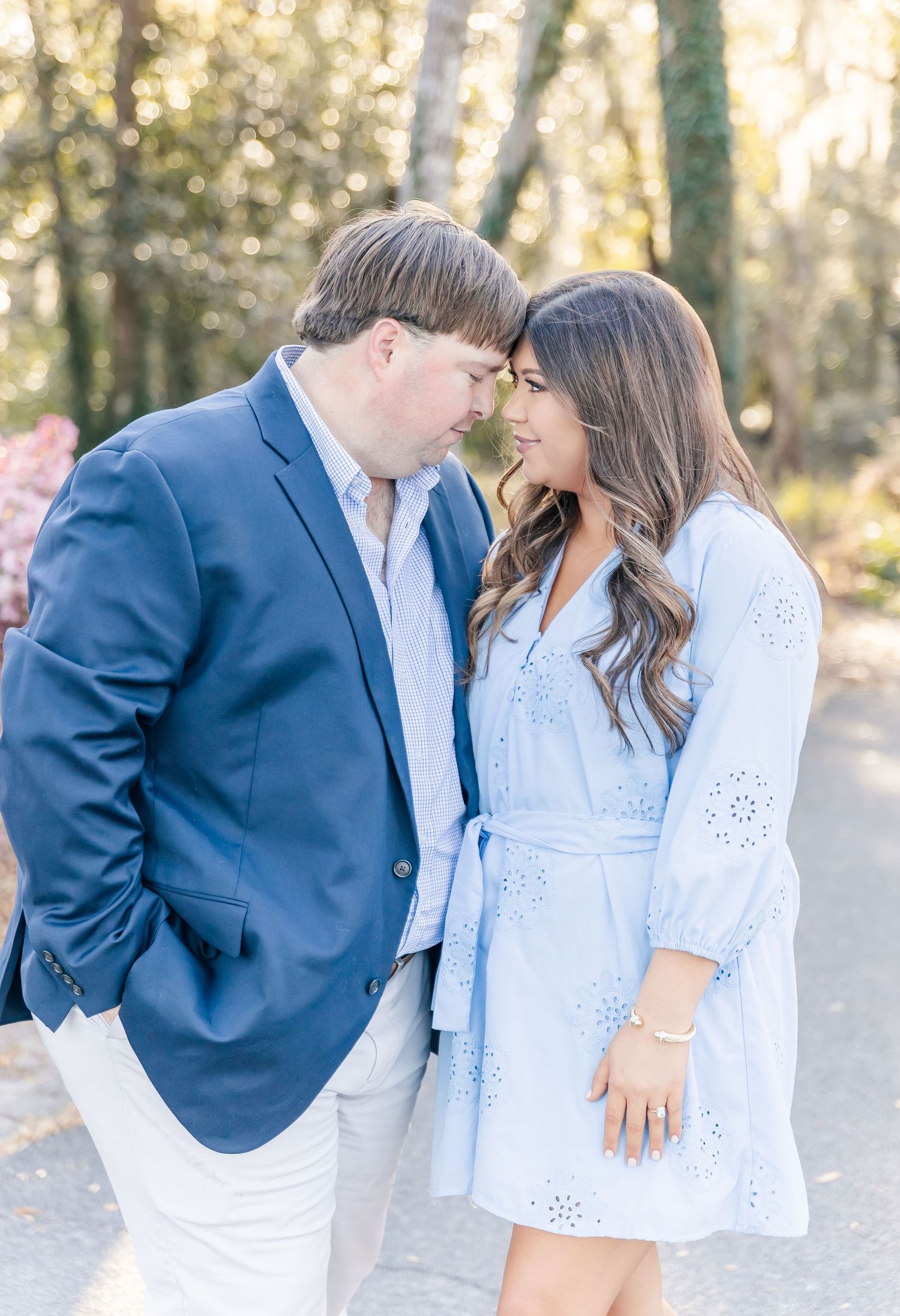 A tender moment captured between a couple in coordinated blue and white outfits against a natural backdrop.