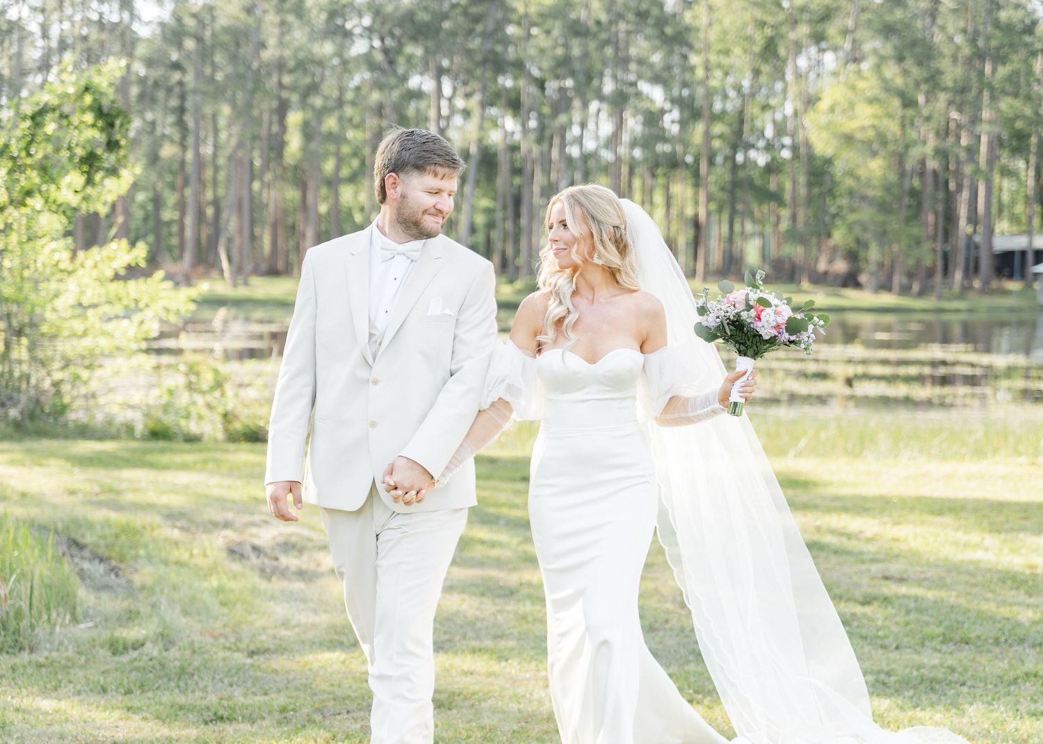Candid shot of bride and groom walking together in sunlit garden setting.