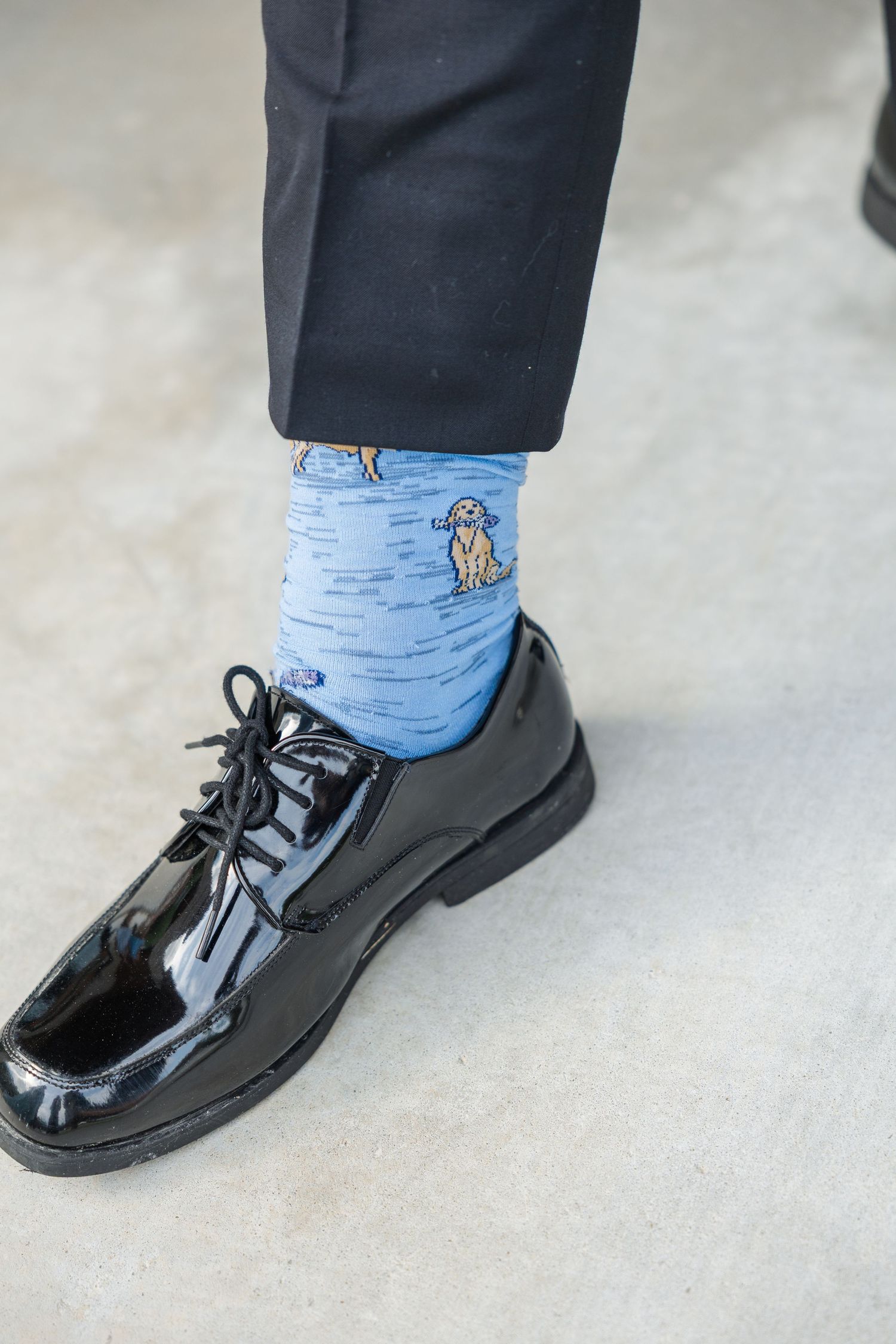 Groom wearing fun blue dog-print socks with black patent leather dress shoes and dark suit trousers.