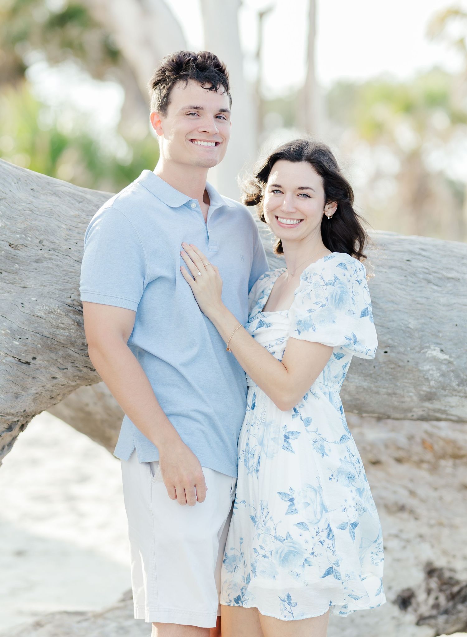 A romantic beach photoshoot with a couple in light blue attire against a natural backdrop.