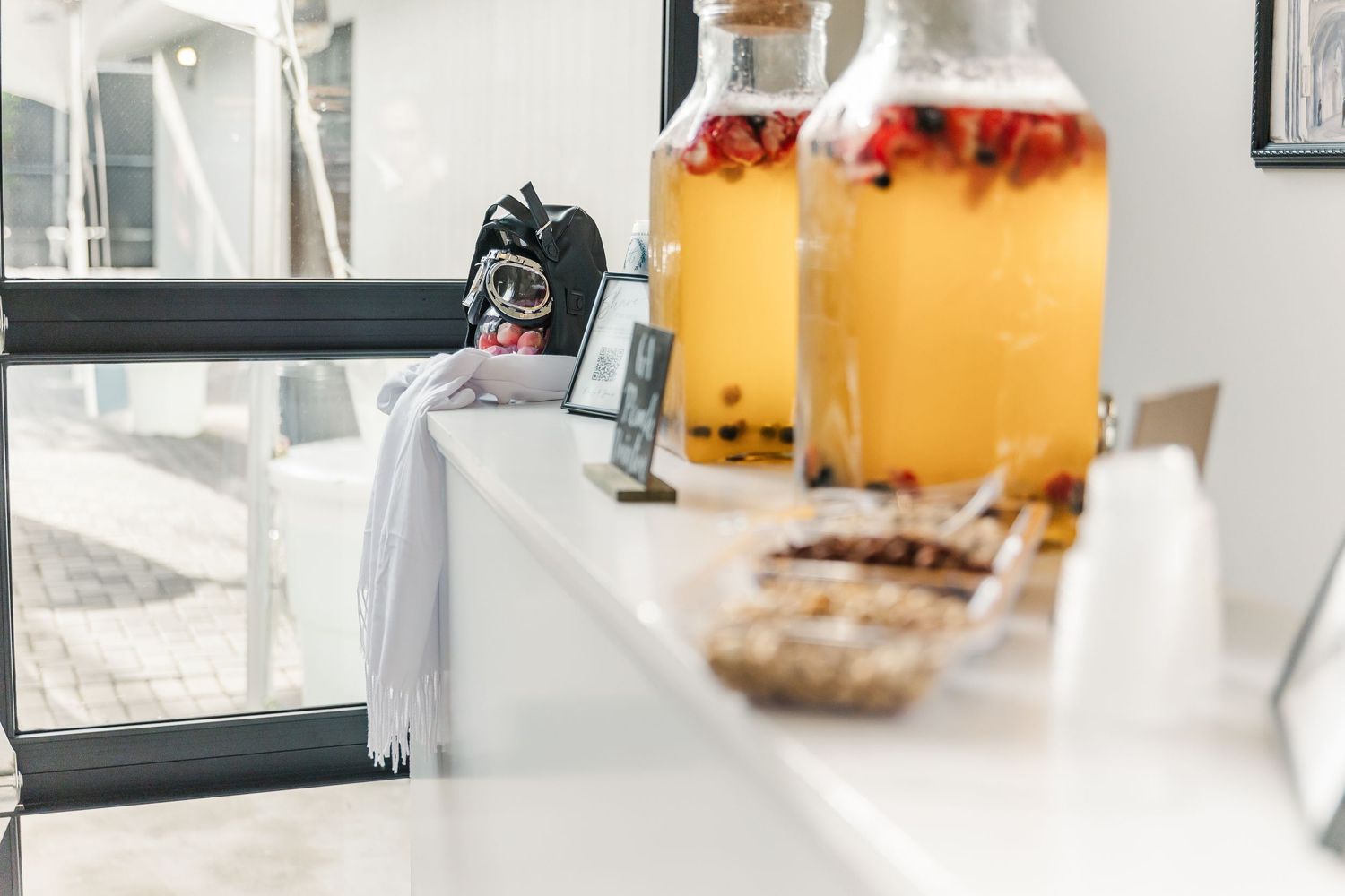 Glass bottles of infused drinks and snacks arranged on a white counter surface.