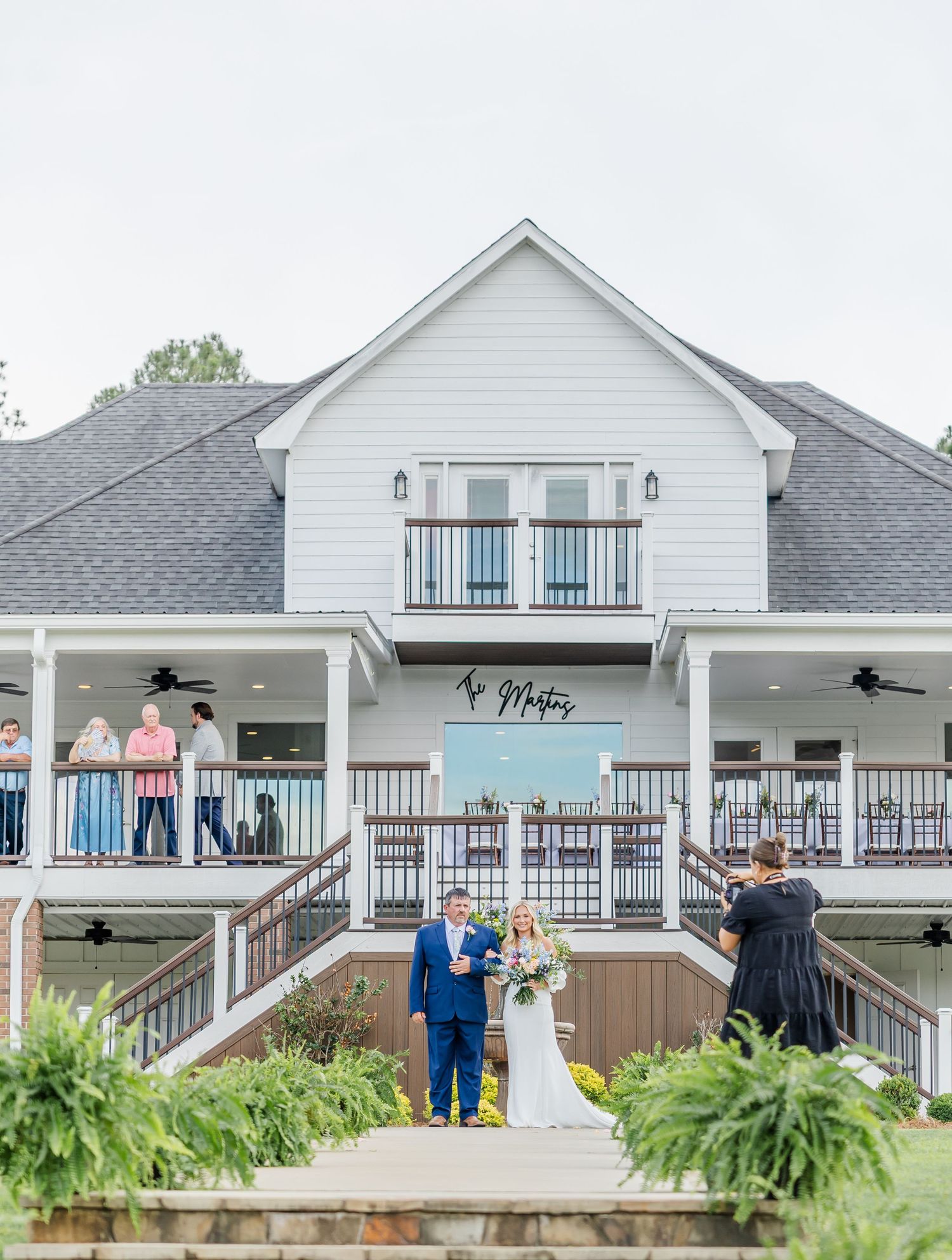 Bride and groom stand before officiant during outdoor wedding ceremony at lakeside venue.