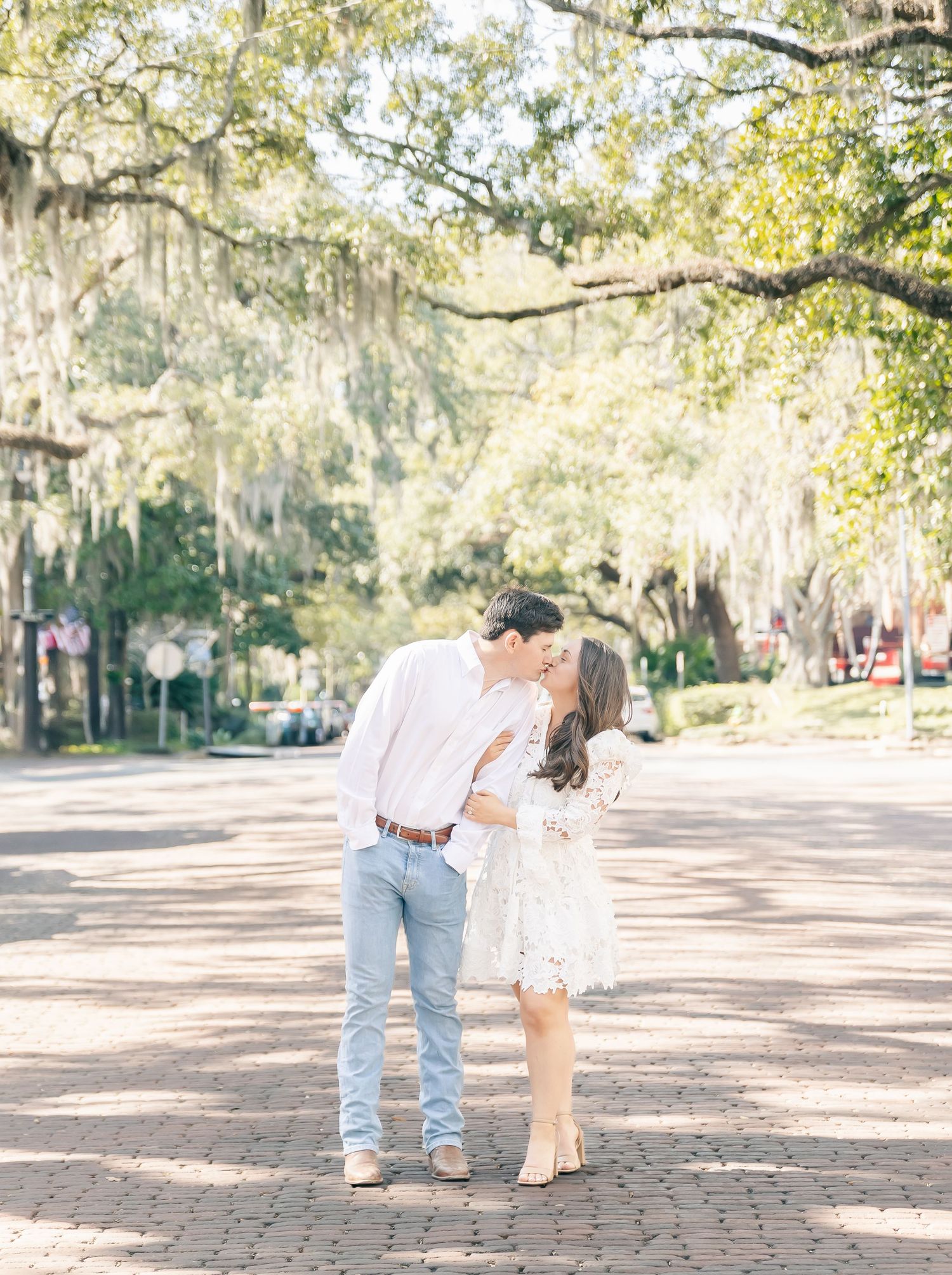 A couple shares an intimate moment on a tree-lined brick street in a Southern town.