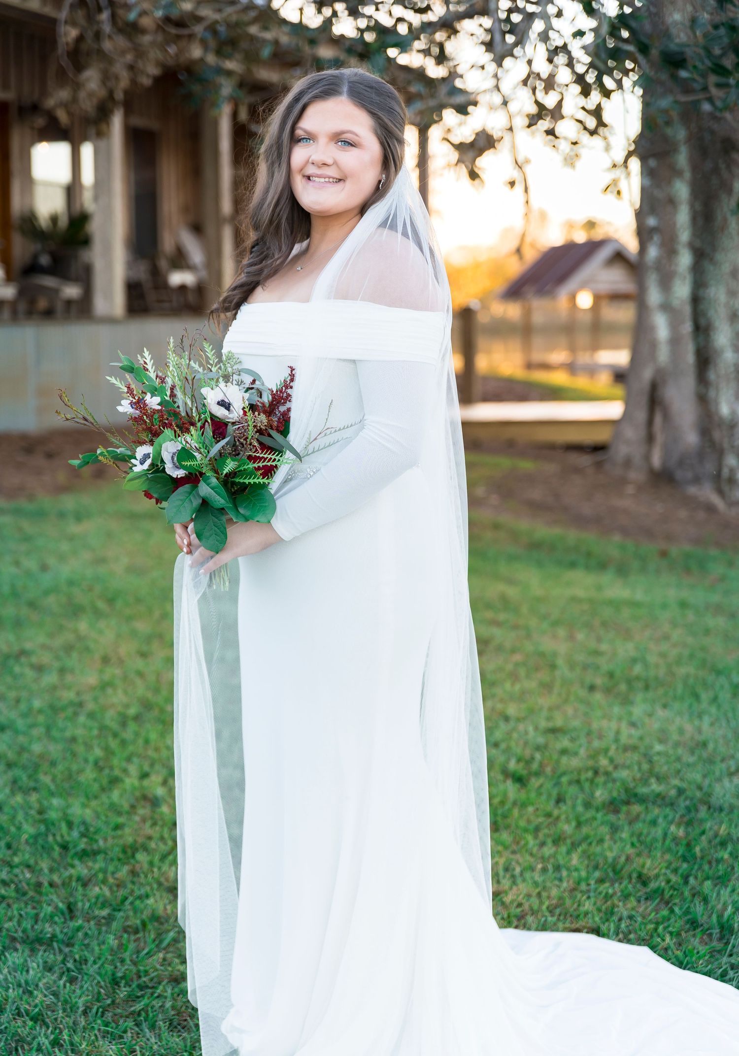 An elegant off-shoulder wedding dress with stunning bouquet captured during golden hour outdoors.