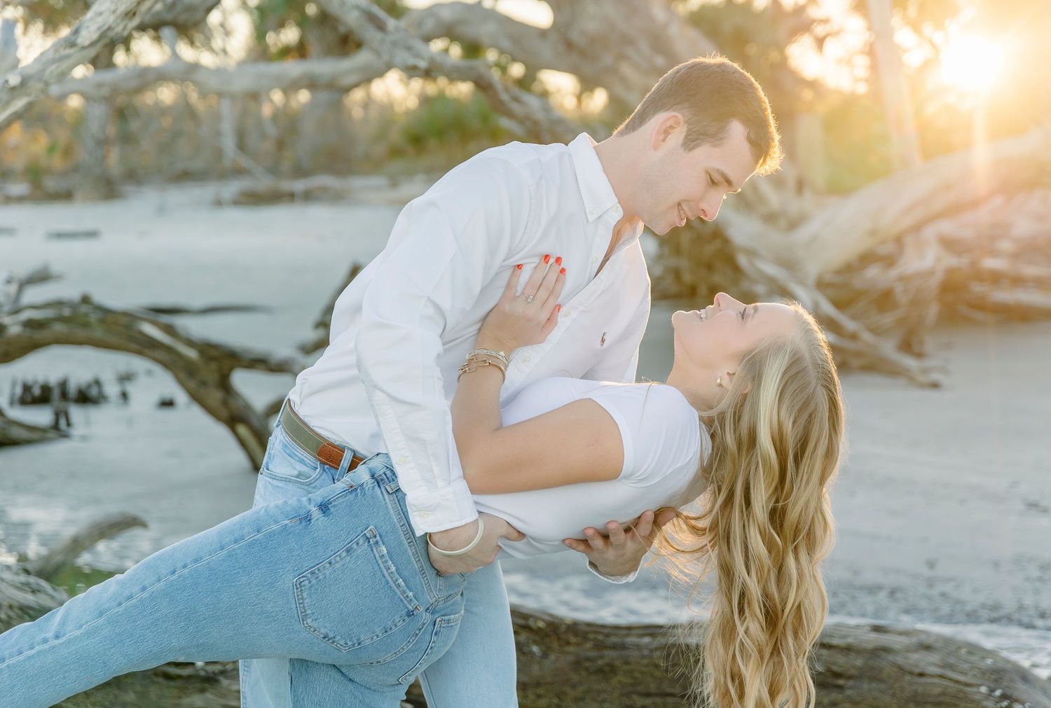 Romantic dip pose between couple on beach with golden sunlight behind them.