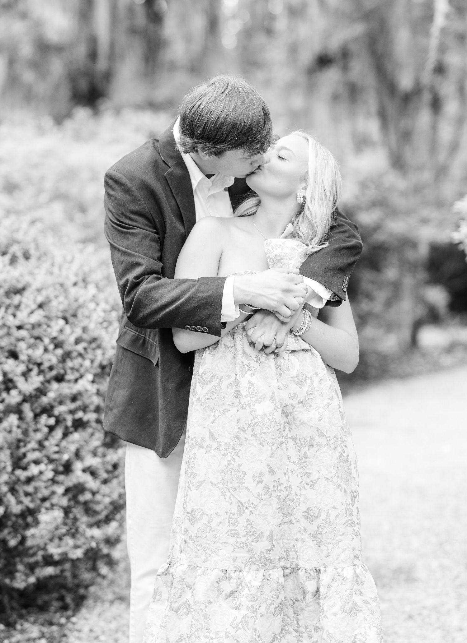 Black and white wedding photo series showing romantic moment between couple in formal attire outdoors.