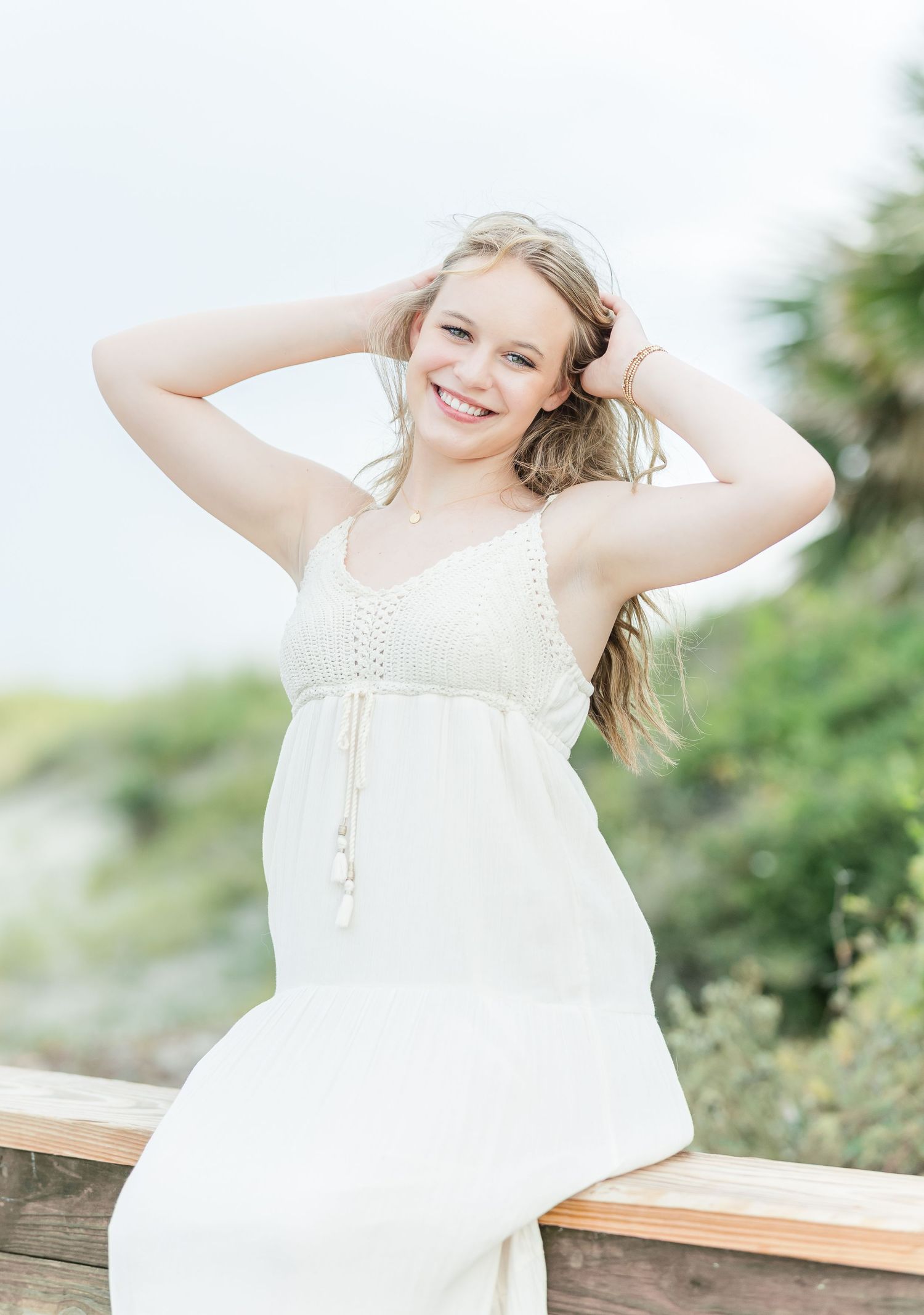 A white sundress-clad figure poses playfully against a natural outdoor background.