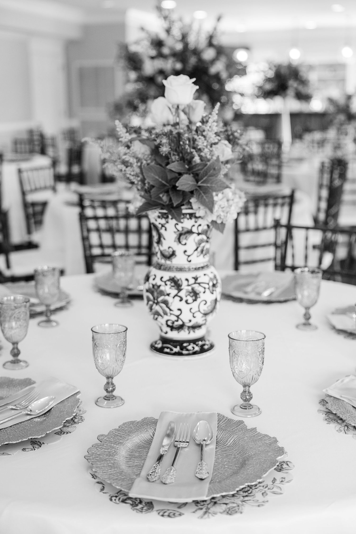 Elegant black and white wedding reception table with floral centerpiece, crystal goblets, and decorative charger plates.