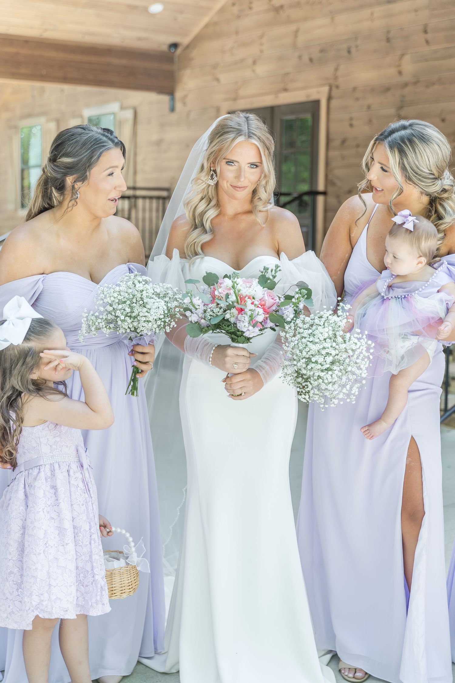 Candid moment of bridal party sharing laughter while holding floral bouquets.