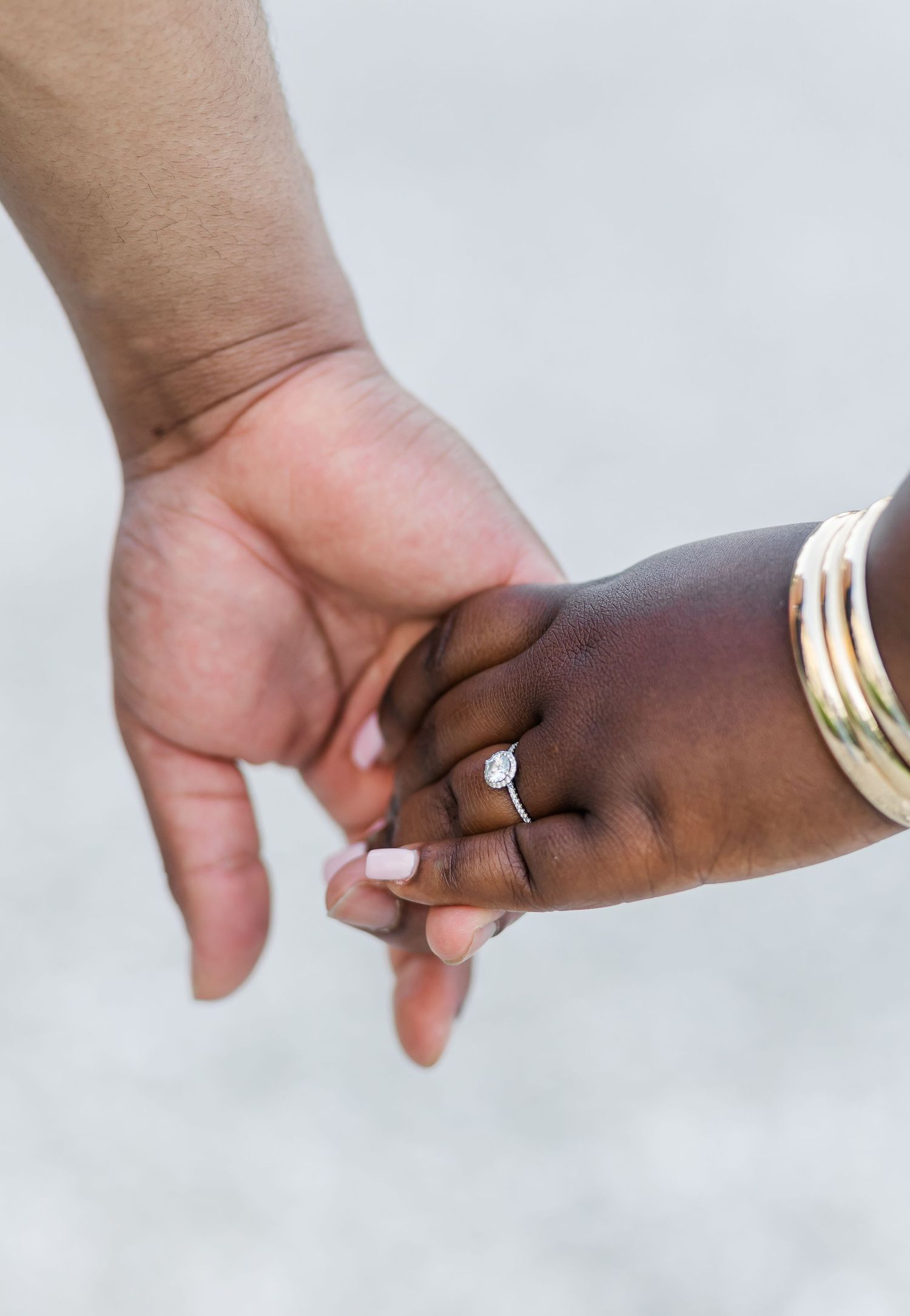 Close-up of hands with engagement ring and bracelets.